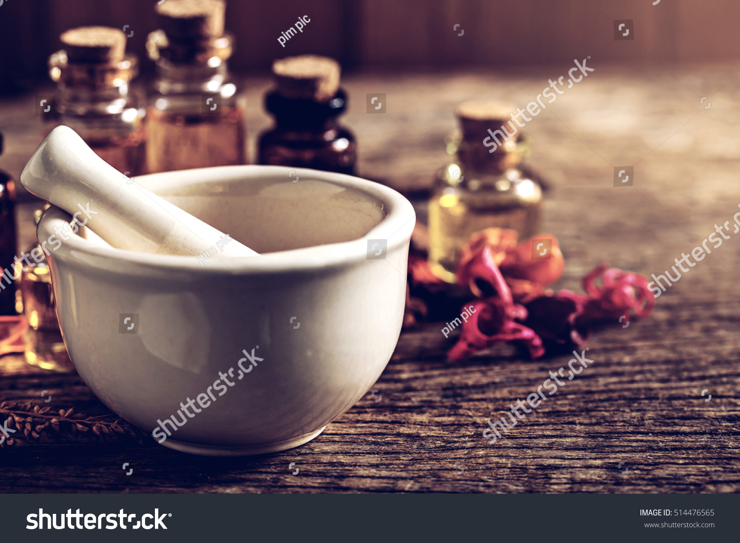 mortar and bottle of aroma essential oil with dry flower on wooden table, spa concept.vintage color tone. #514476565
