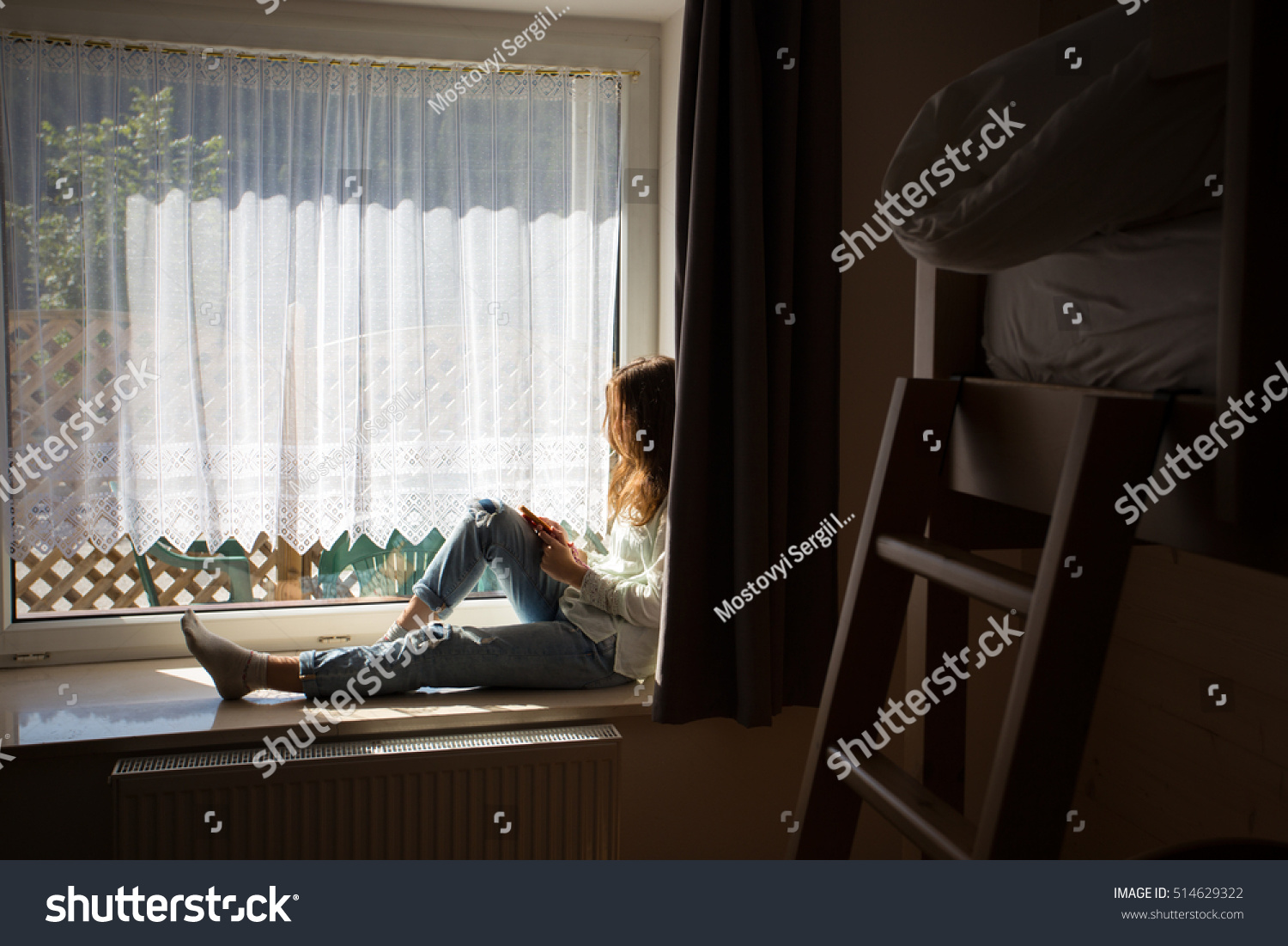 teen girl sitting on a windowsill with a smartphone in the children's room
 #514629322