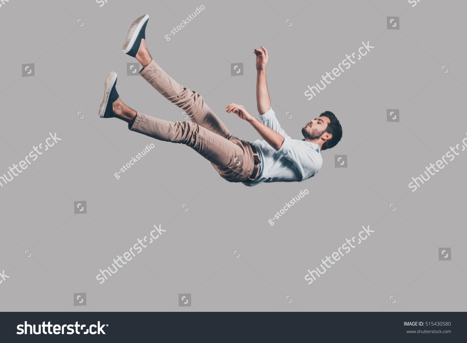 Man falling down. Mid-air shot of handsome young man falling against grey background  #515430580