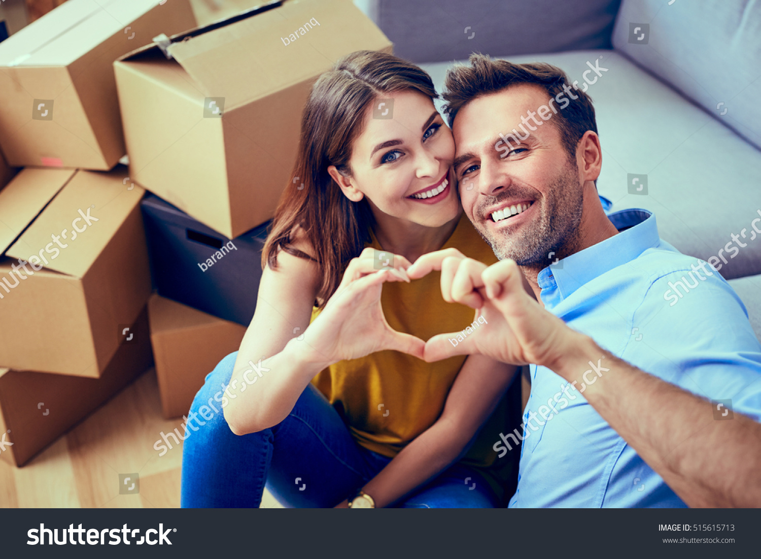 Happy couple during moving house showing heart sign #515615713