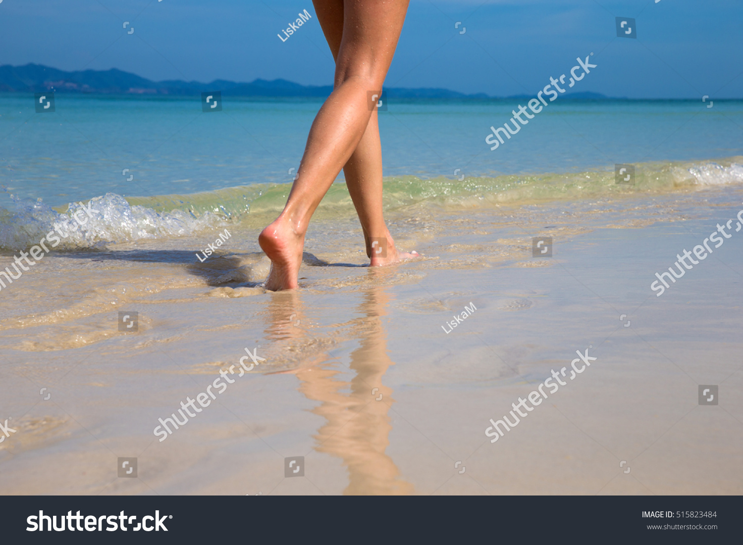 Woman walking on sand beach leaving footprints in the sand #515823484