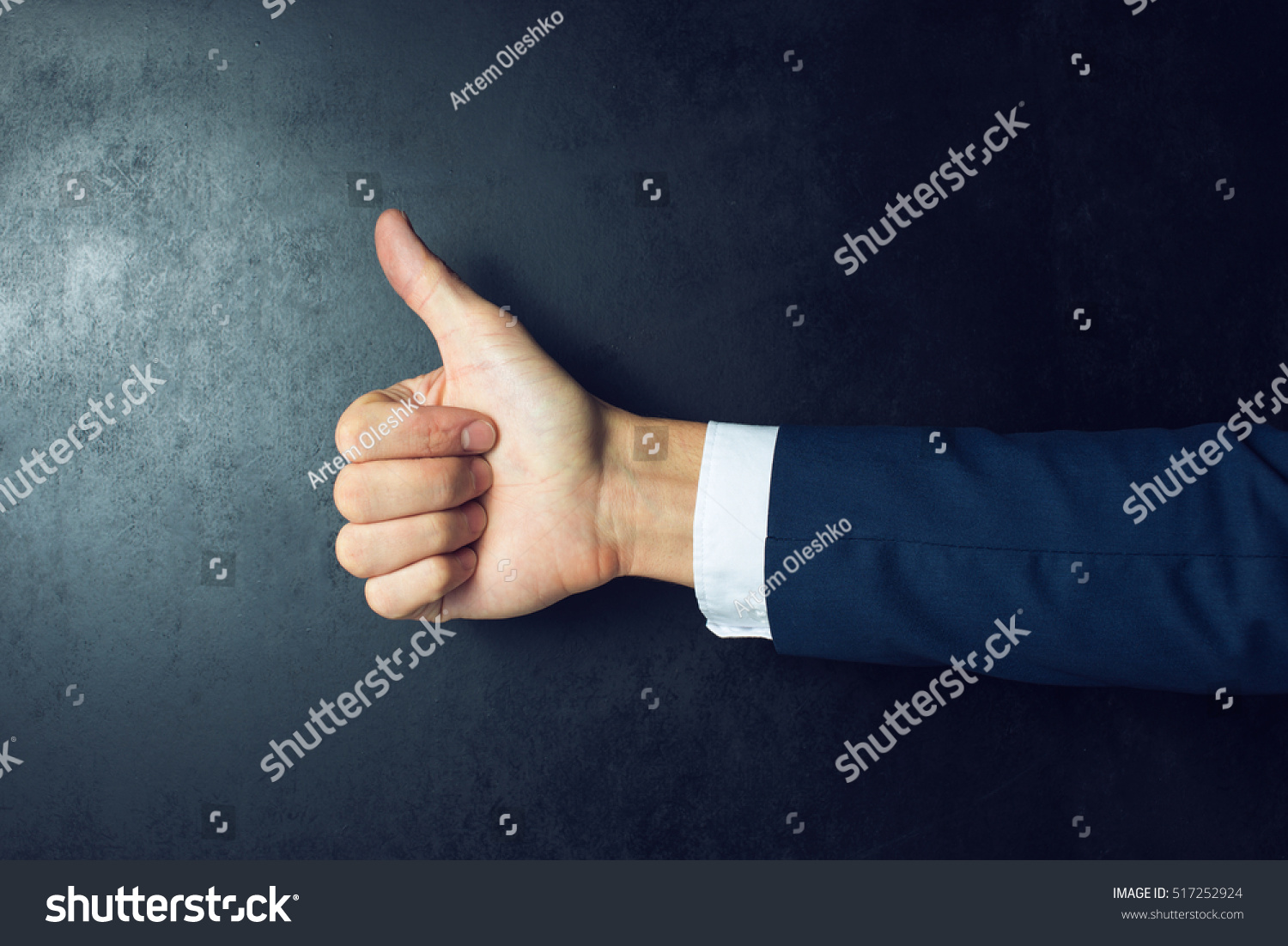 Like this. Close-up of human hand with thumb up in front of the blackboard #517252924
