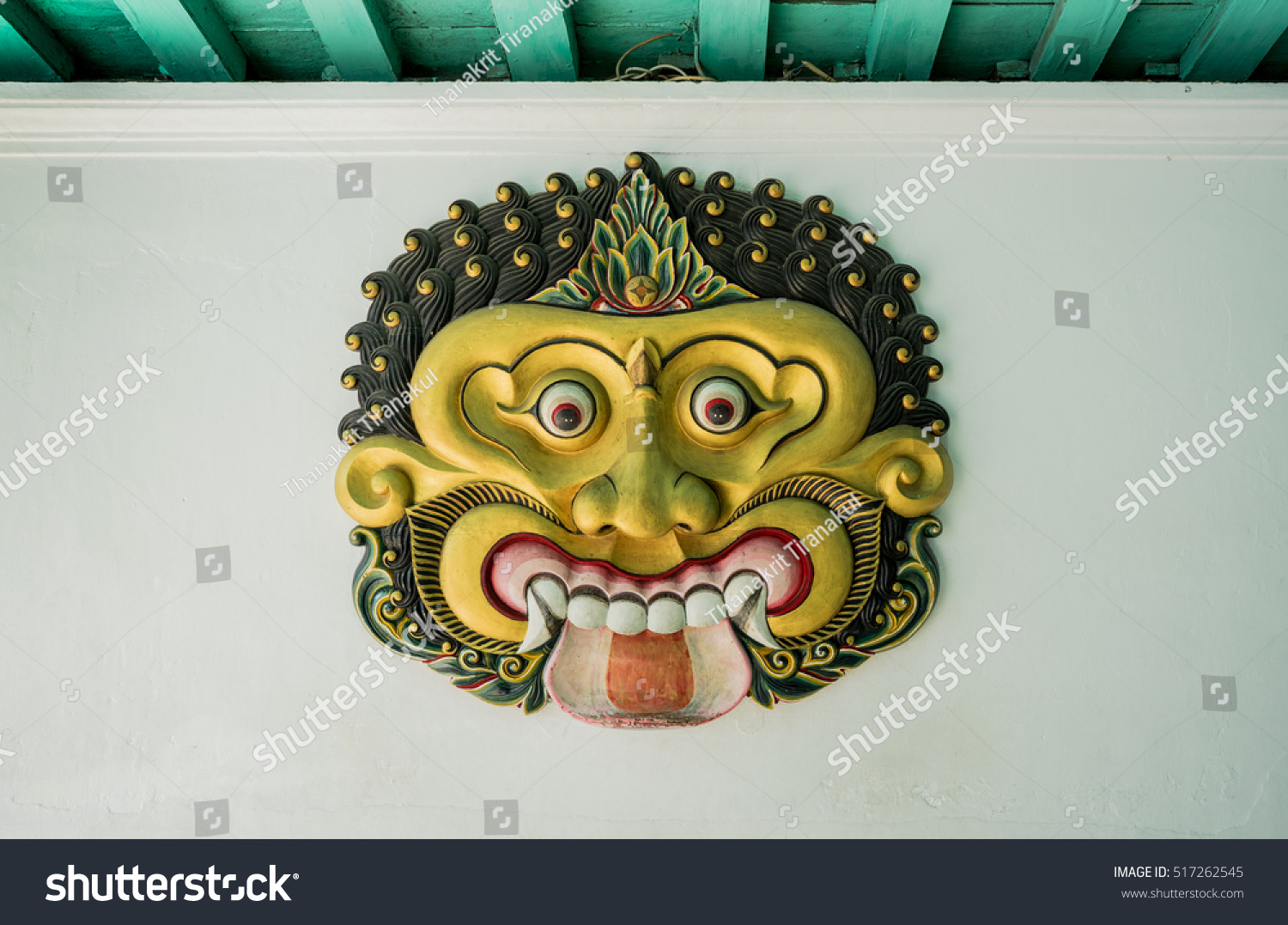 the  golden giant mask on the white wall inside of the very old castle in Indonesia #517262545