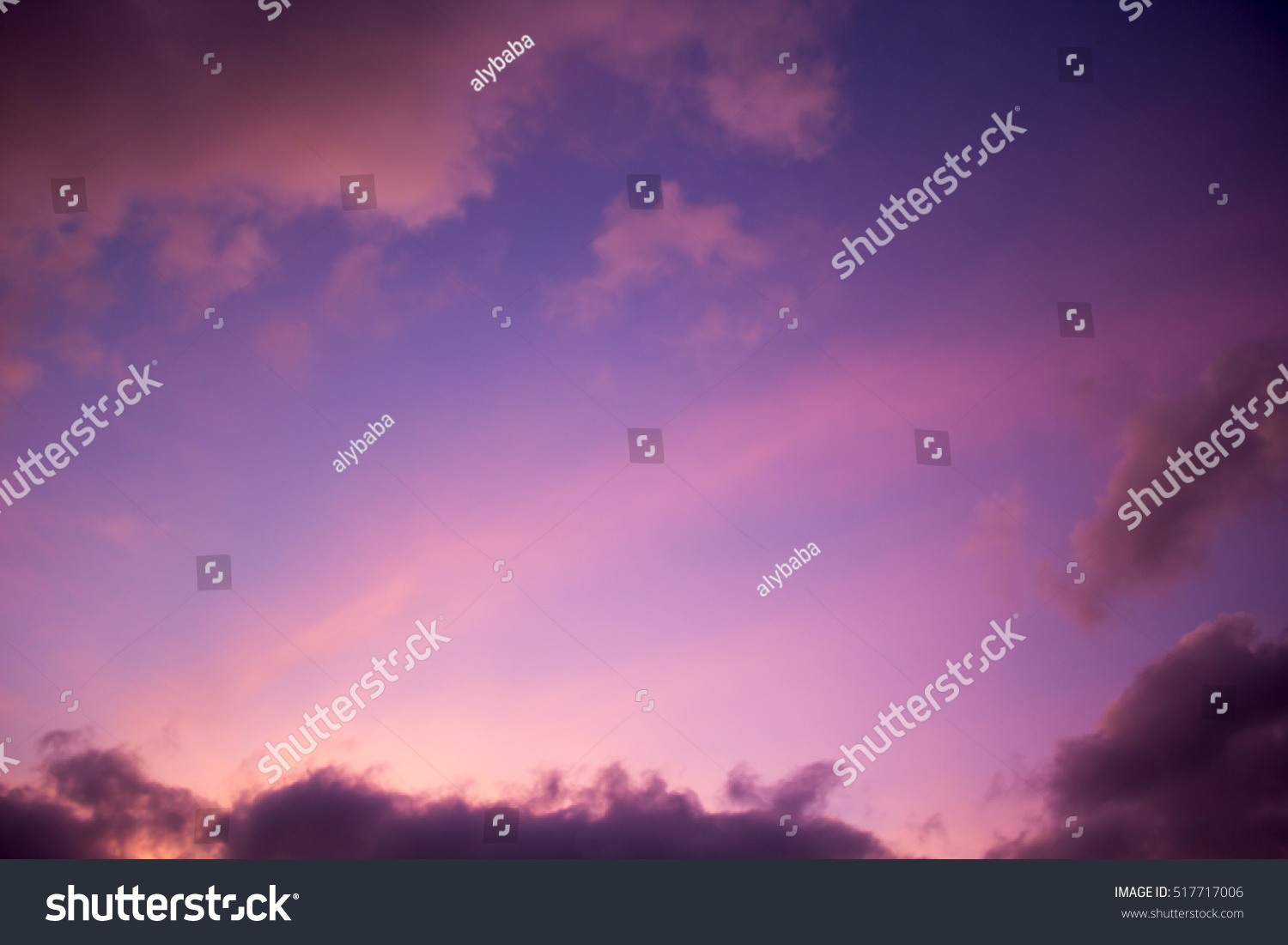 Clouds at sunset  in tropical Broome, North Western Australia  are beautifully hued with soft salmon pink, grey and  pale blue tones as the hot sun sinks into the Indian Ocean  in summer #517717006