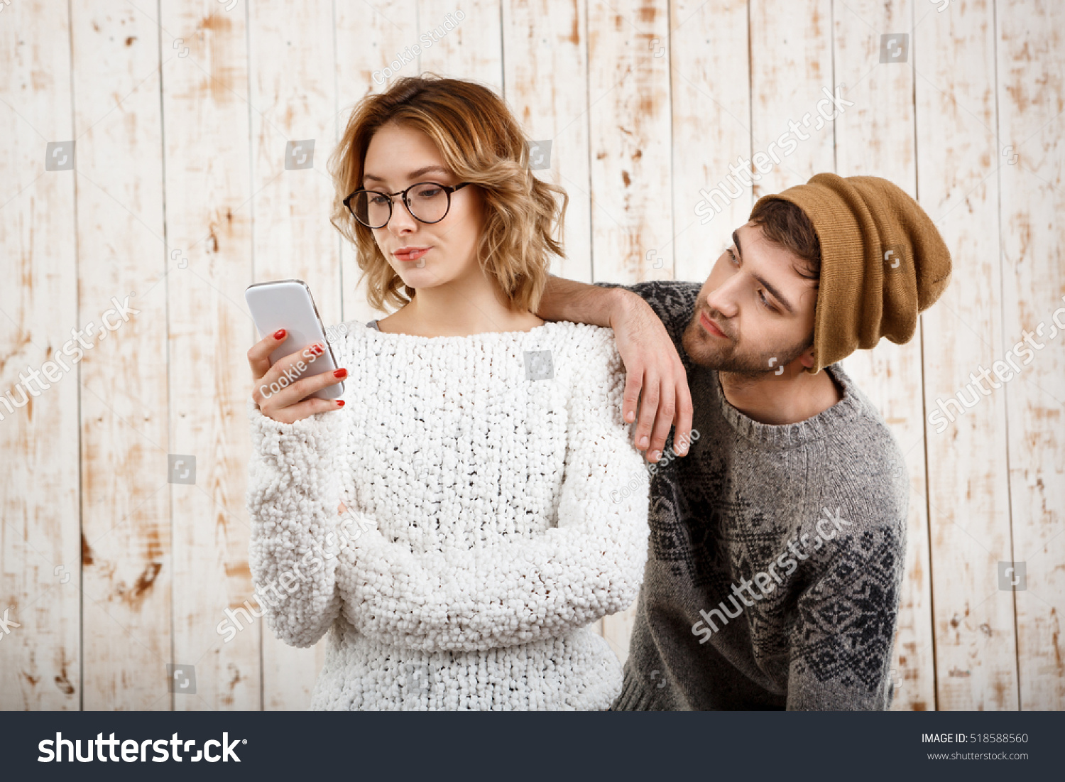 Man unnerve his girlfriend looking at phone over wooden background. #518588560
