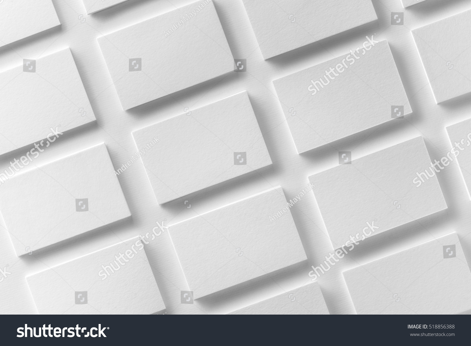 Mockup of horizontal business cards stacks arranged in rows at white textured paper background. #518856388