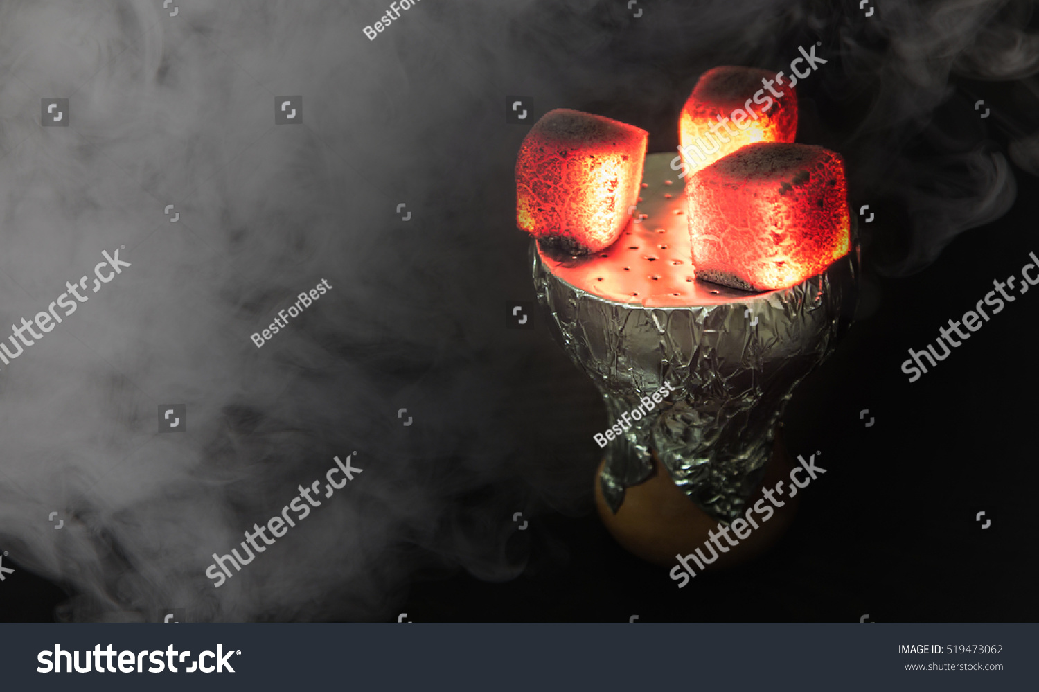 Shisha bowl with craft tobacco and red coil with hookah smoke background. #519473062