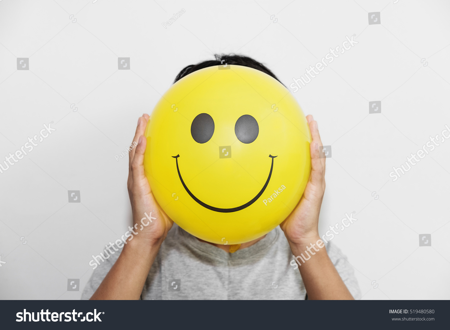 A man holding yellow balloon with smile face emotion instead of head. Positive Thinking concepts. hiding some bad feeling just keep smiling #519480580