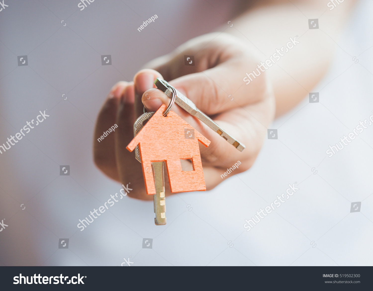 Female hand holding house key,real estate agent. #519502300