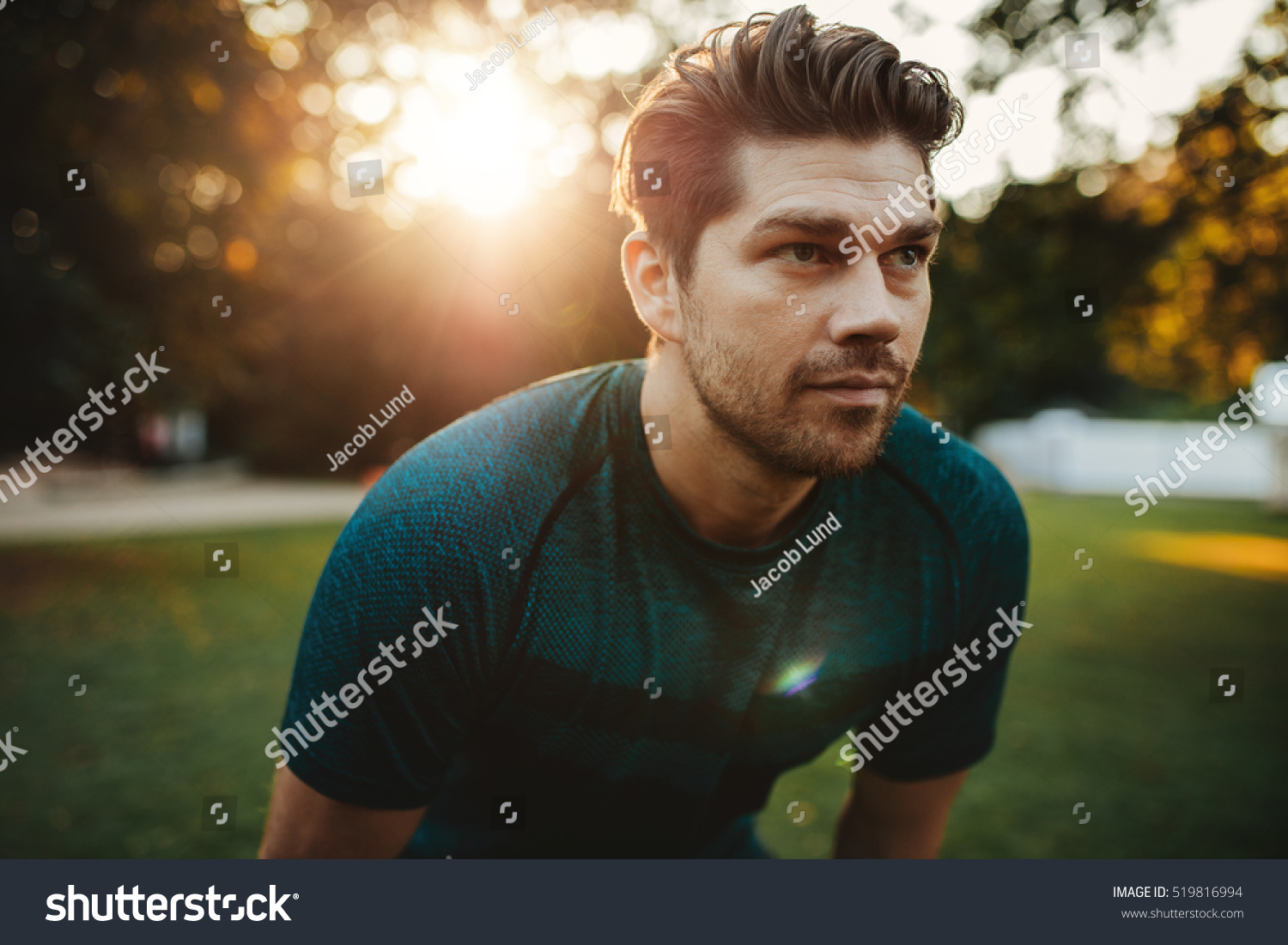 Close up portrait of healthy young man standing outdoors in park and looking away. Confident young man ready of workout. #519816994