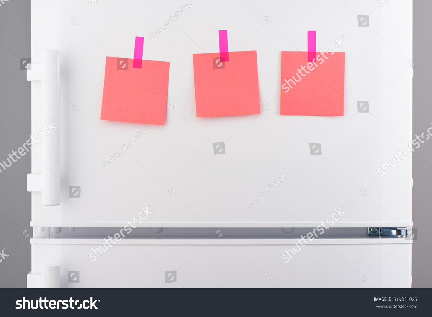 Three blank pink paper notes attached with pink stickers on white refrigerator door #519831025