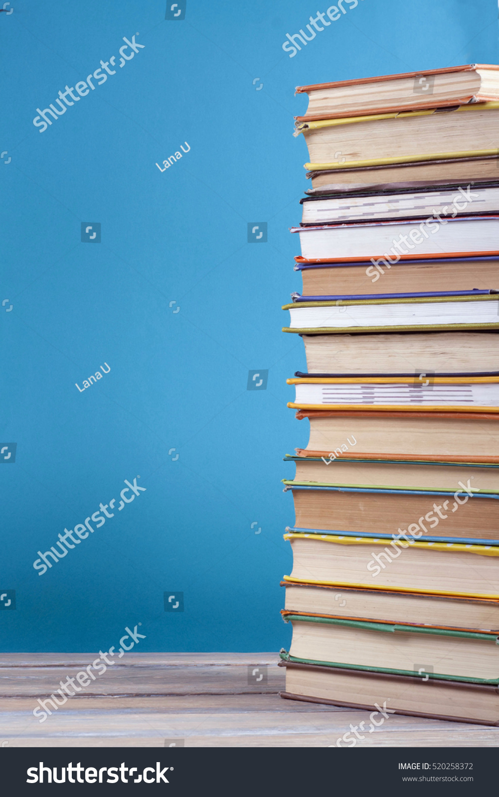 Book stack, hardback colorful books on wooden table and blue background. Back to school. Copy space for text. Education concept. #520258372