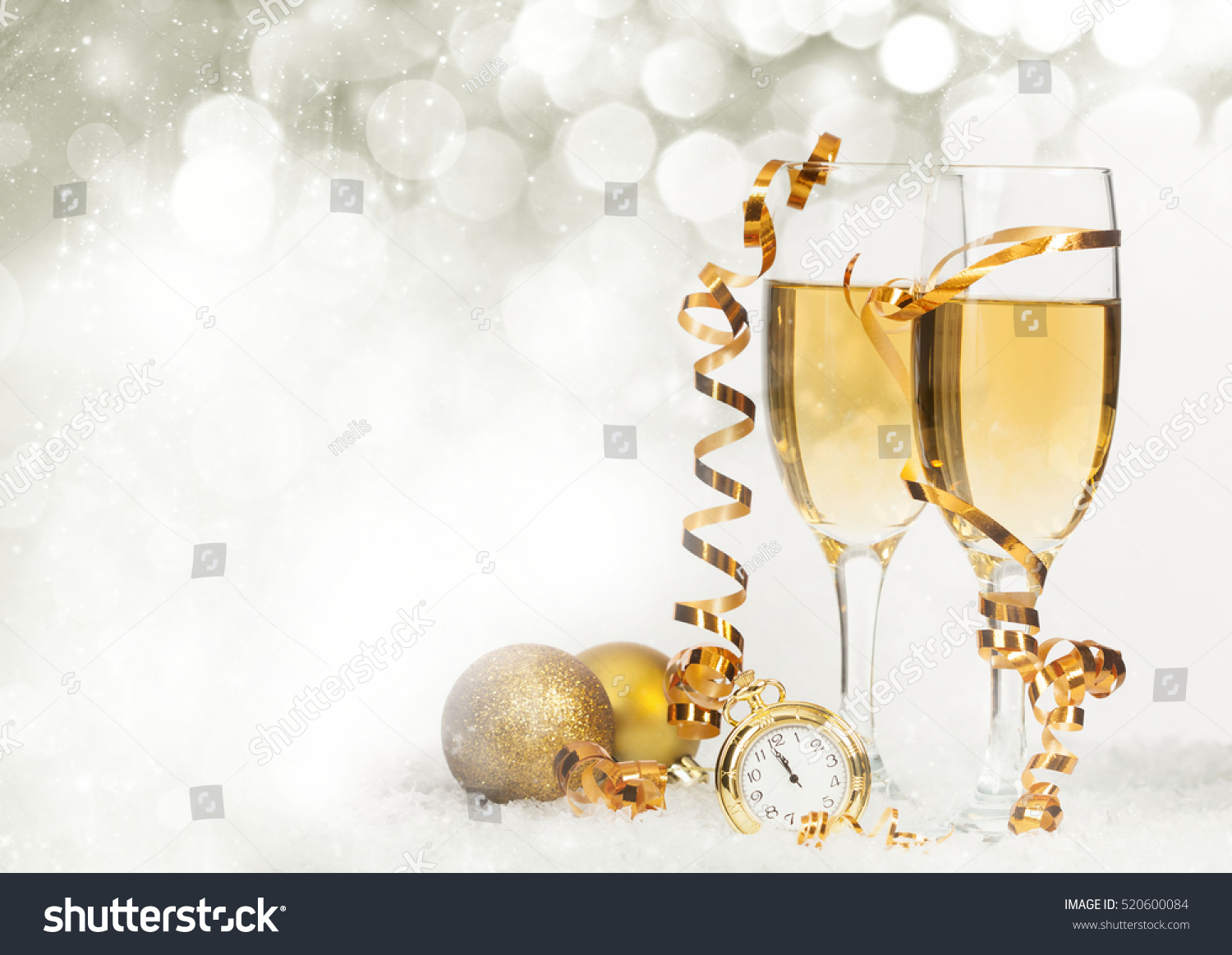 Glasses with champagne and golden Christmas balls against holiday lights - New Year background #520600084