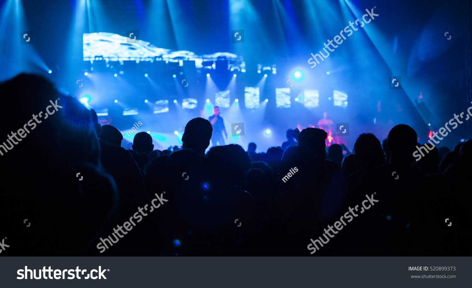 Crowd at concert - Cheering crowd in front of bright colorful stage lights #520899373