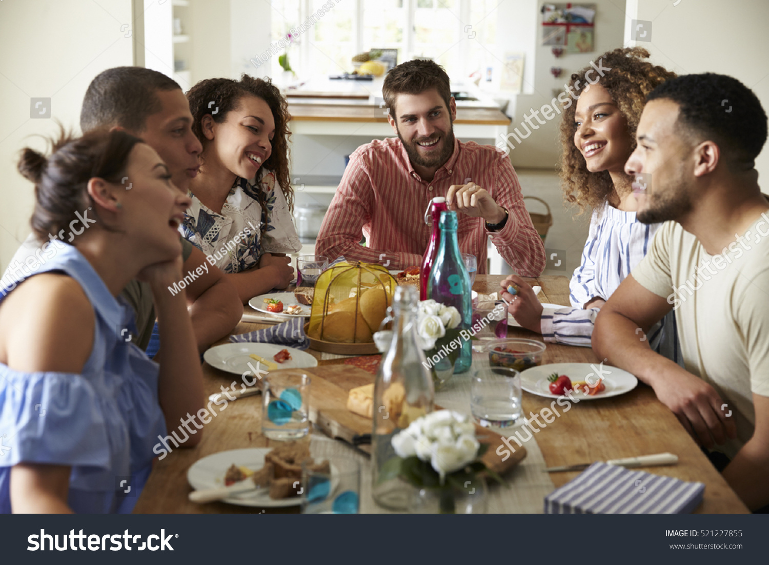 Young adults laughing as they talk at a table over lunch #521227855