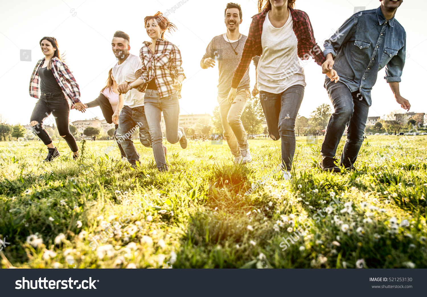 Group of friends running happily together in the grass #521253130