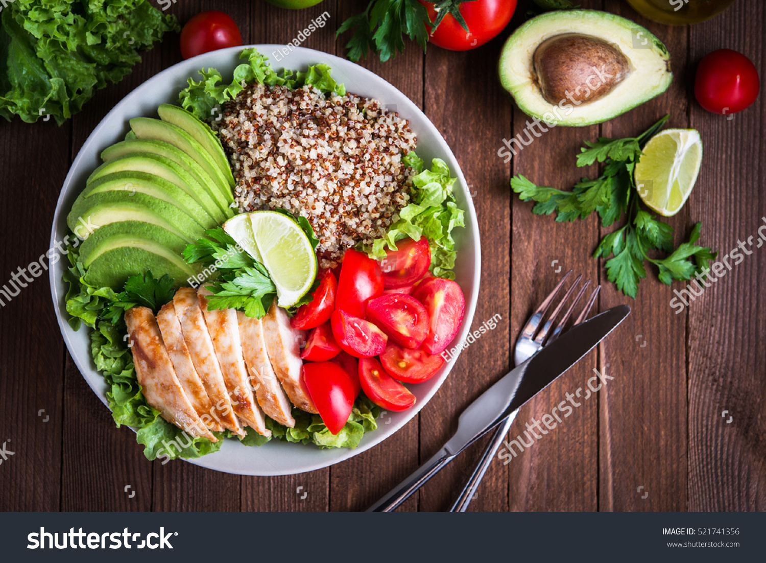 Healthy salad bowl with quinoa, tomatoes, chicken, avocado, lime and mixed greens, lettuce, parsley on wooden background top view. Food and health. #521741356