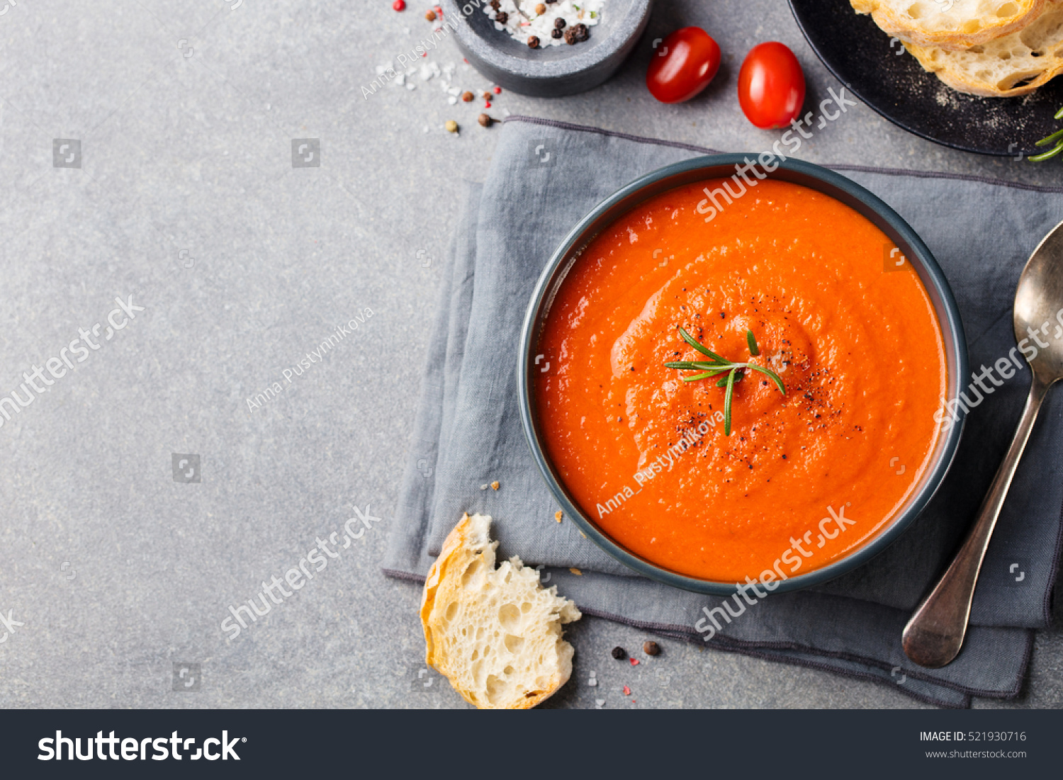 Tomato soup in a black bowl on grey stone background. Top view. Copy space. #521930716