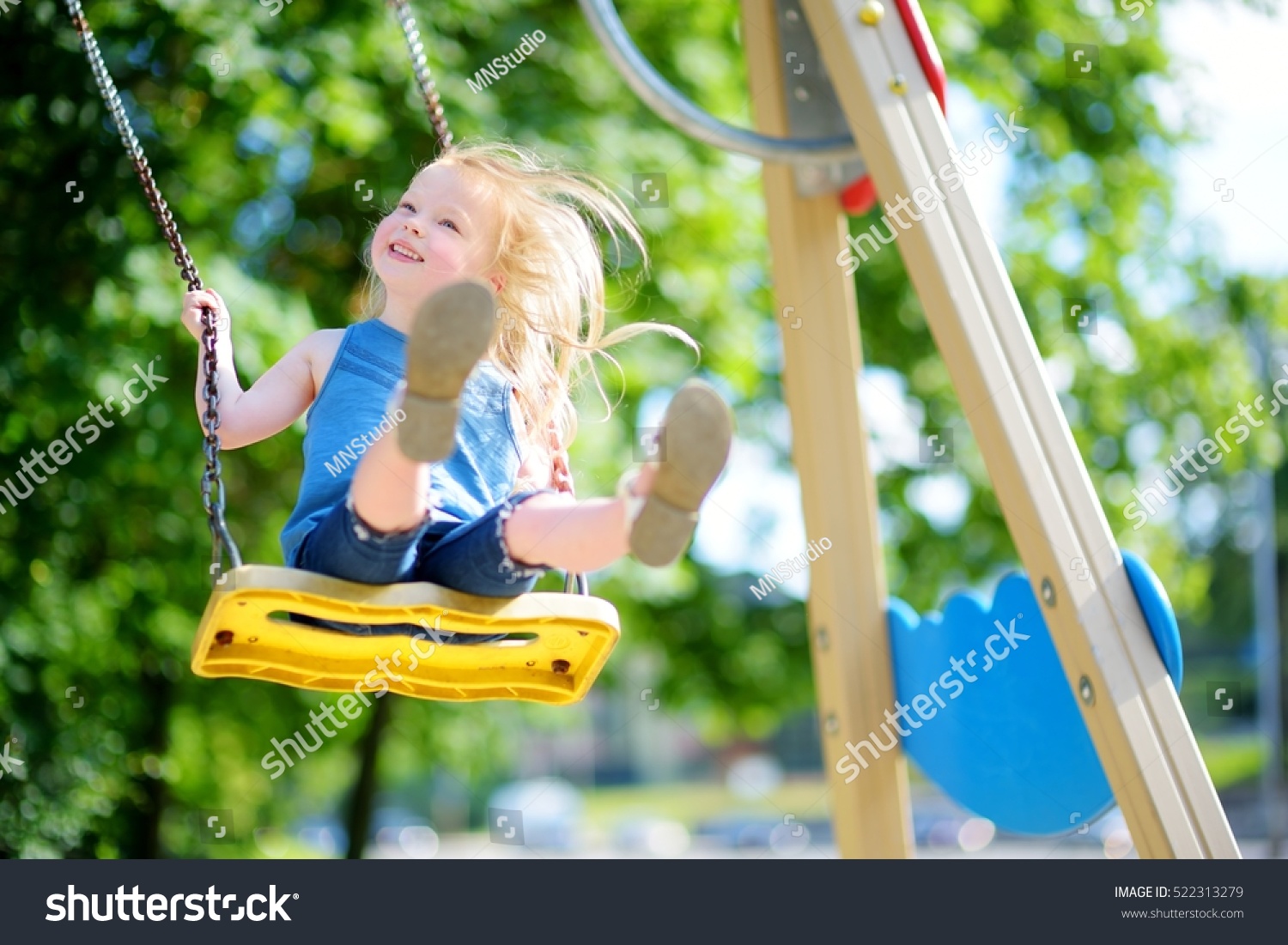 Cute little girl having fun on a playground outdoors in summer #522313279