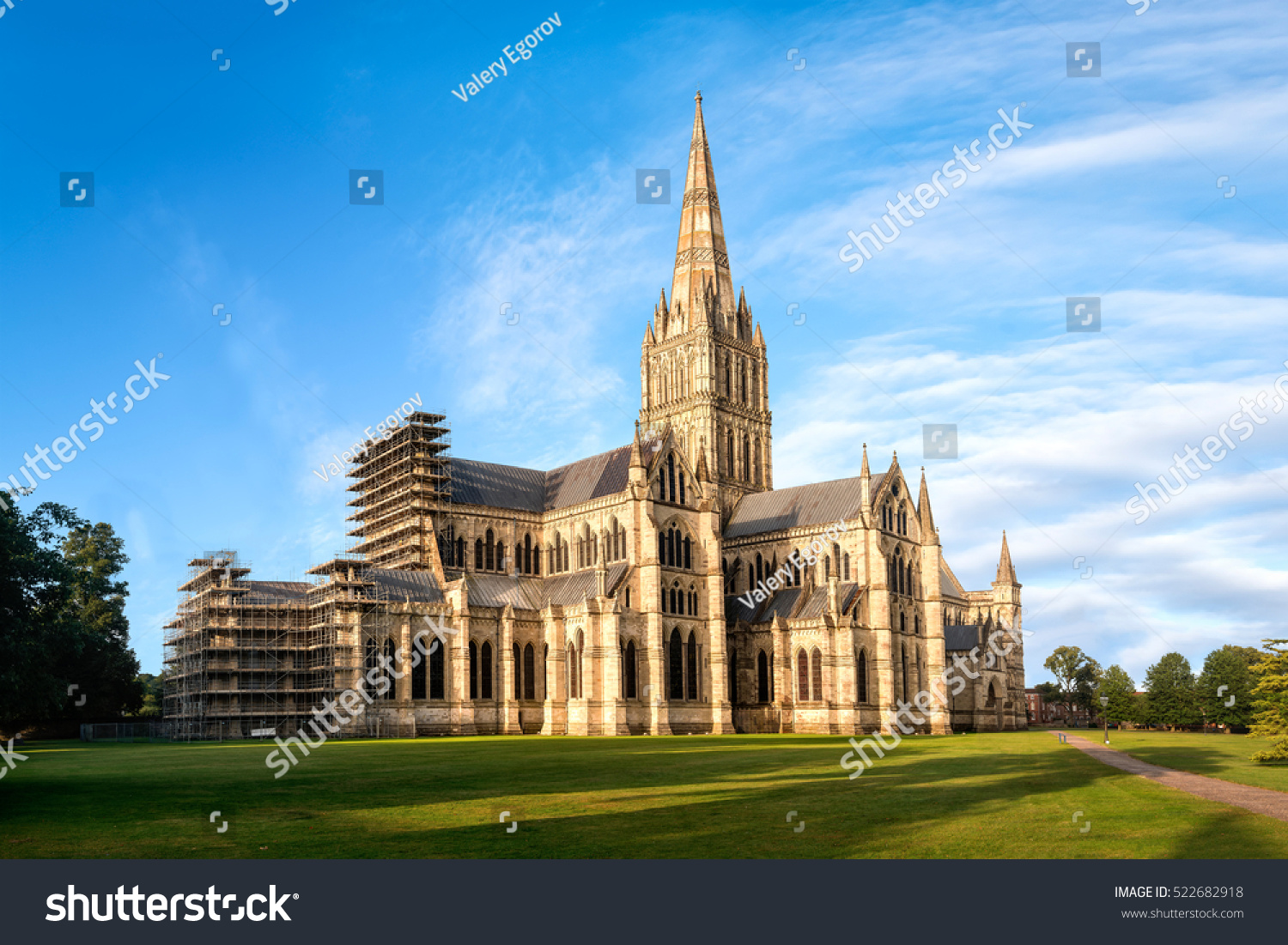 View of Salisbury cathedral church of the Blessed Virgin Mary at sunrise from East. The building is superb example of early english gothic architecture.Copy space in blue sky. #522682918