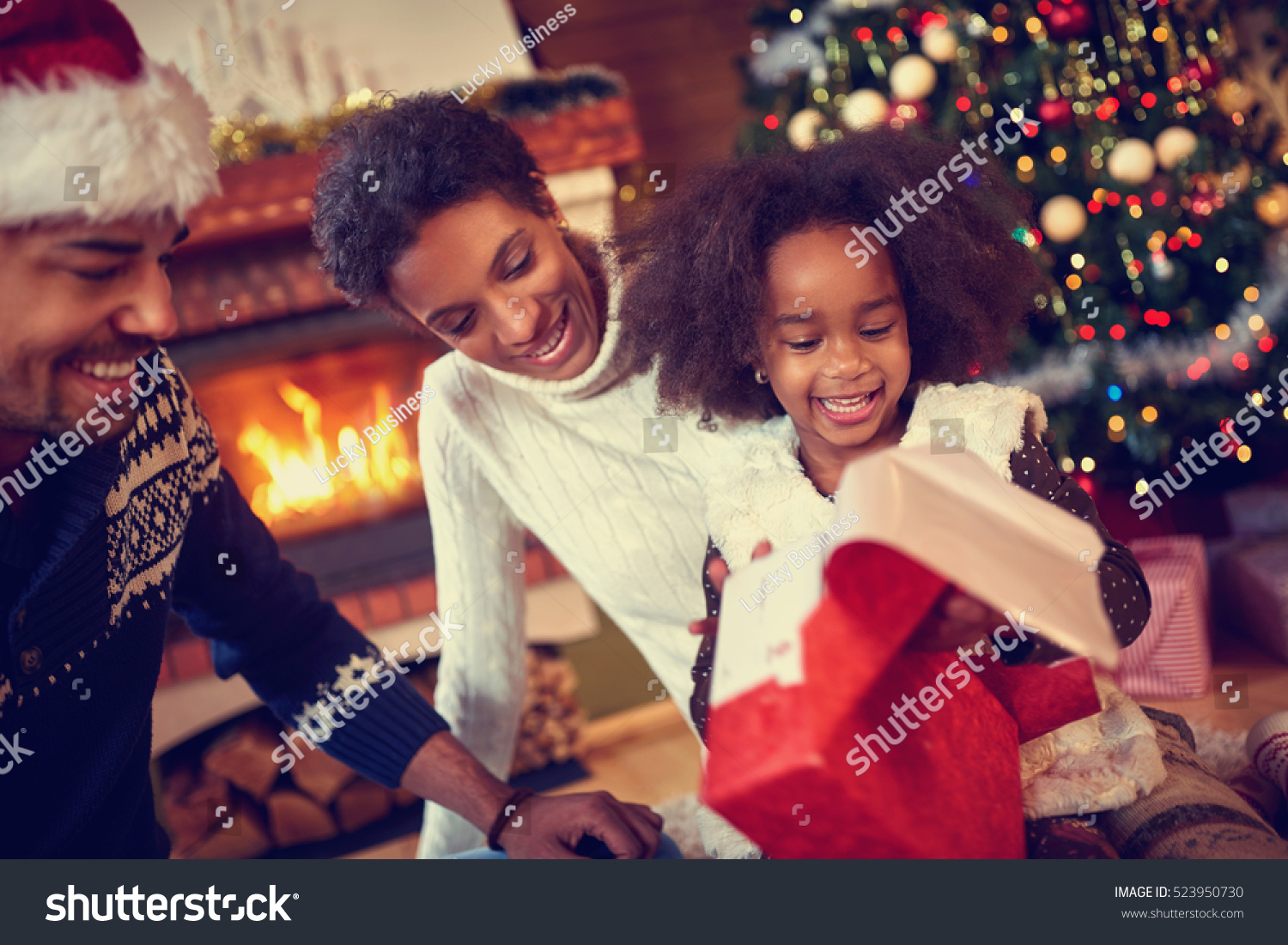 
Happy smiling African American family in Christmas atmosphere opening Christmas present #523950730