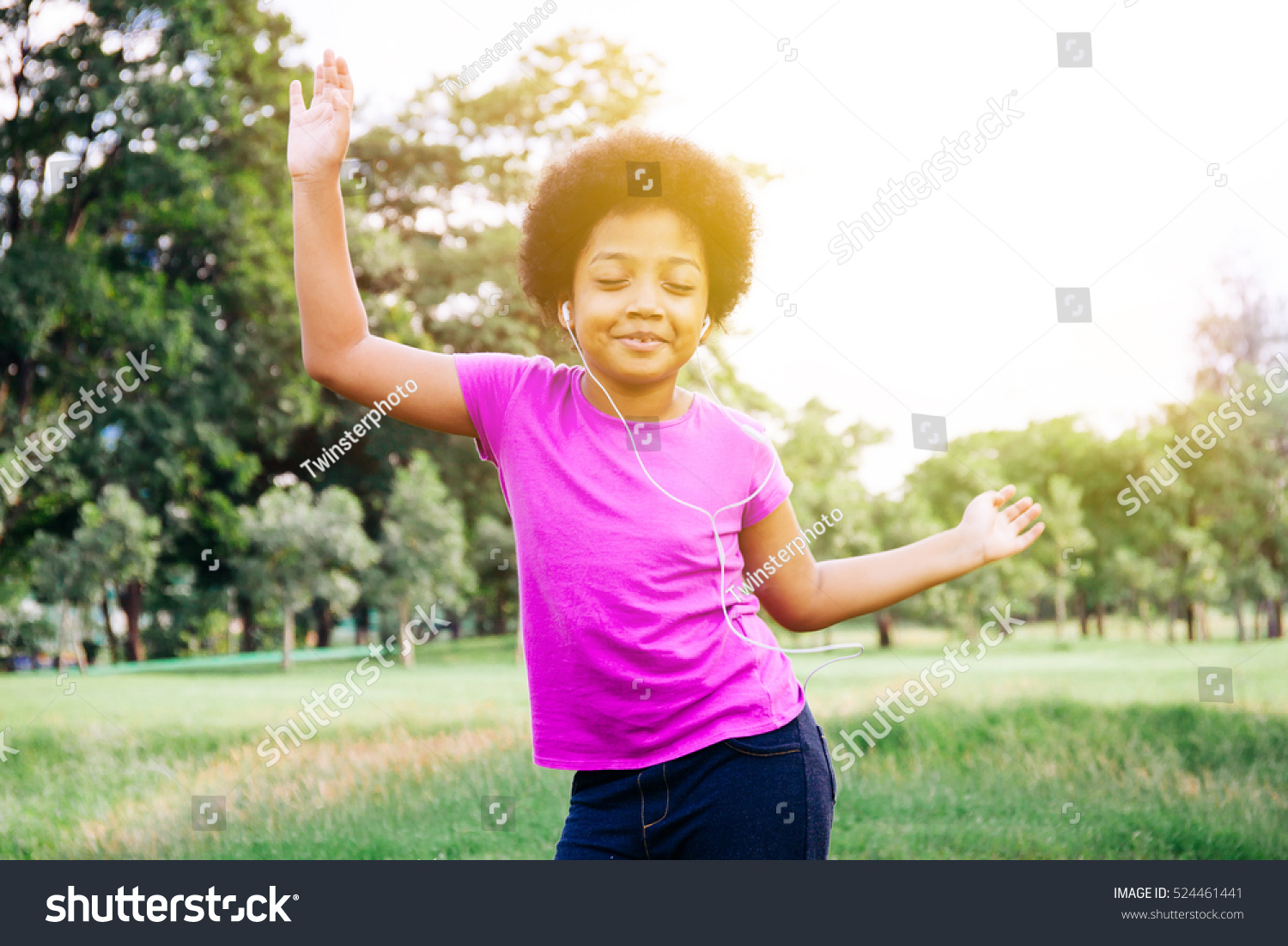 Little kid dancing and listening to music in green park #524461441