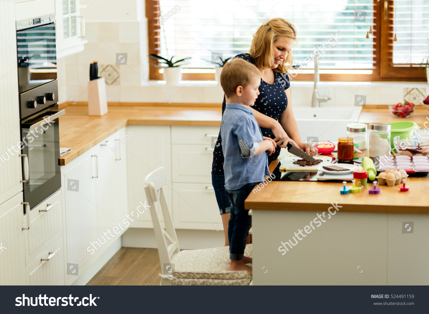 Smart cute child helping mother in kitchen preparing cookies #524491159