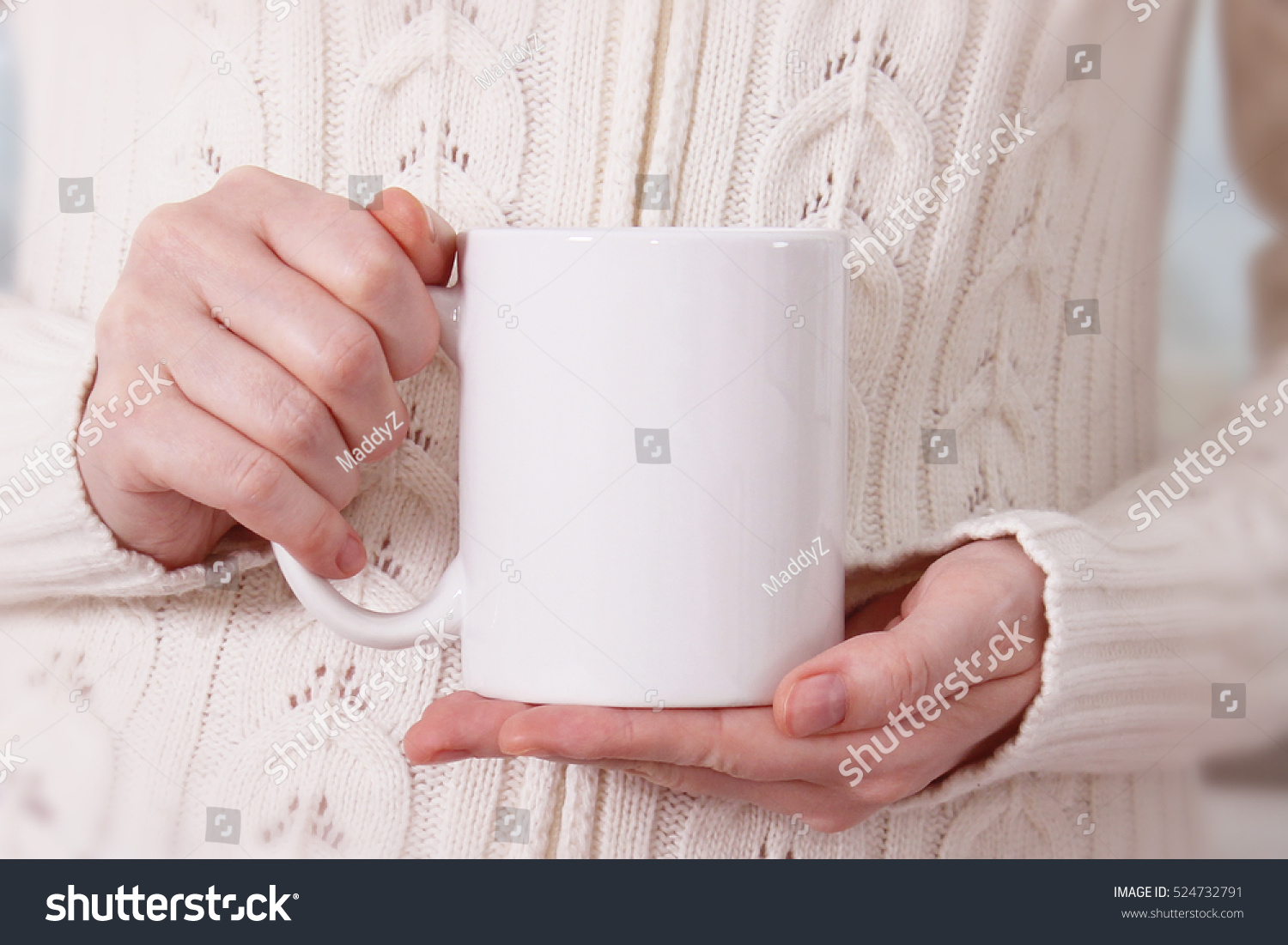 Girl in warm sweater is holding white mug in hands.. Mockup for winter gifts design. #524732791