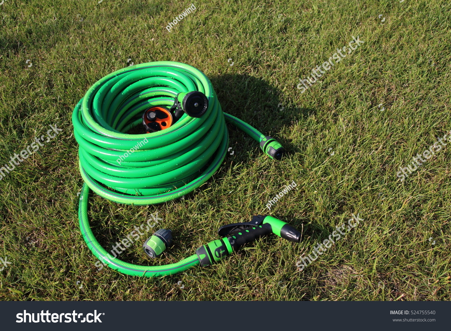 Garden hose bundle, connector and various adjustable showers (spray) on the mown lawn in the summer garden #524755540