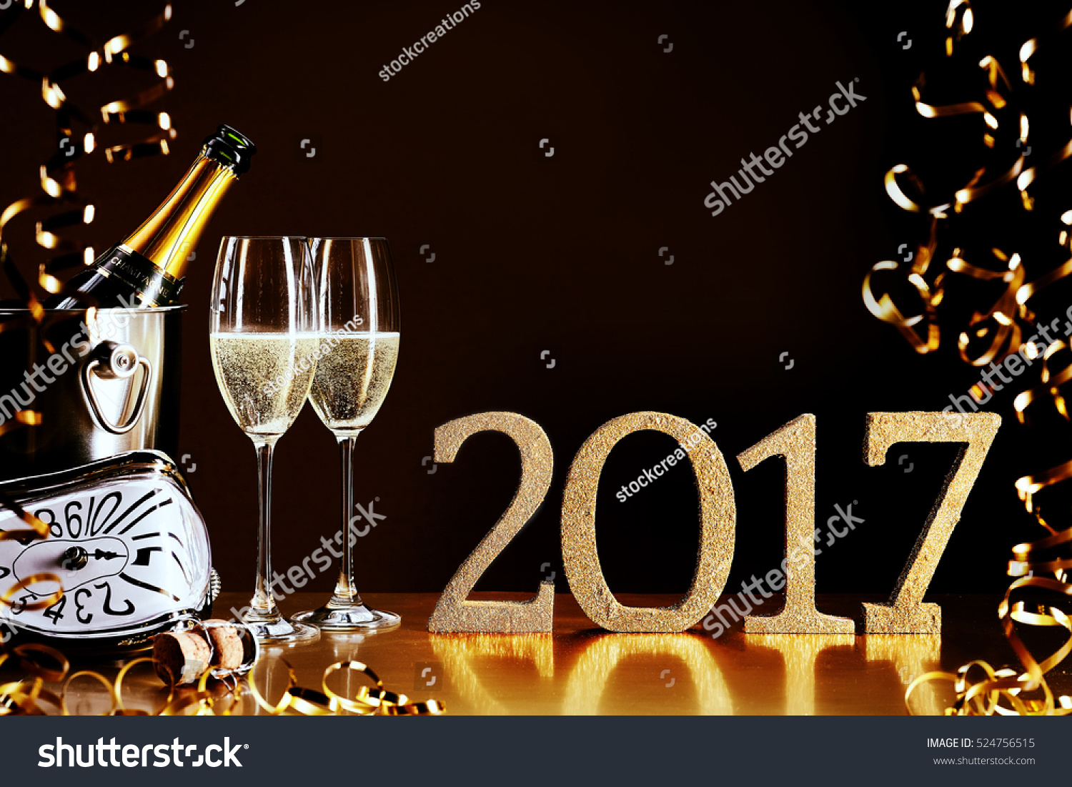 2017 New Year celebration with a bottle and flutes of chilled champagne, golden party streamers and a modern clock counting down to midnight, copy space for your greeting #524756515