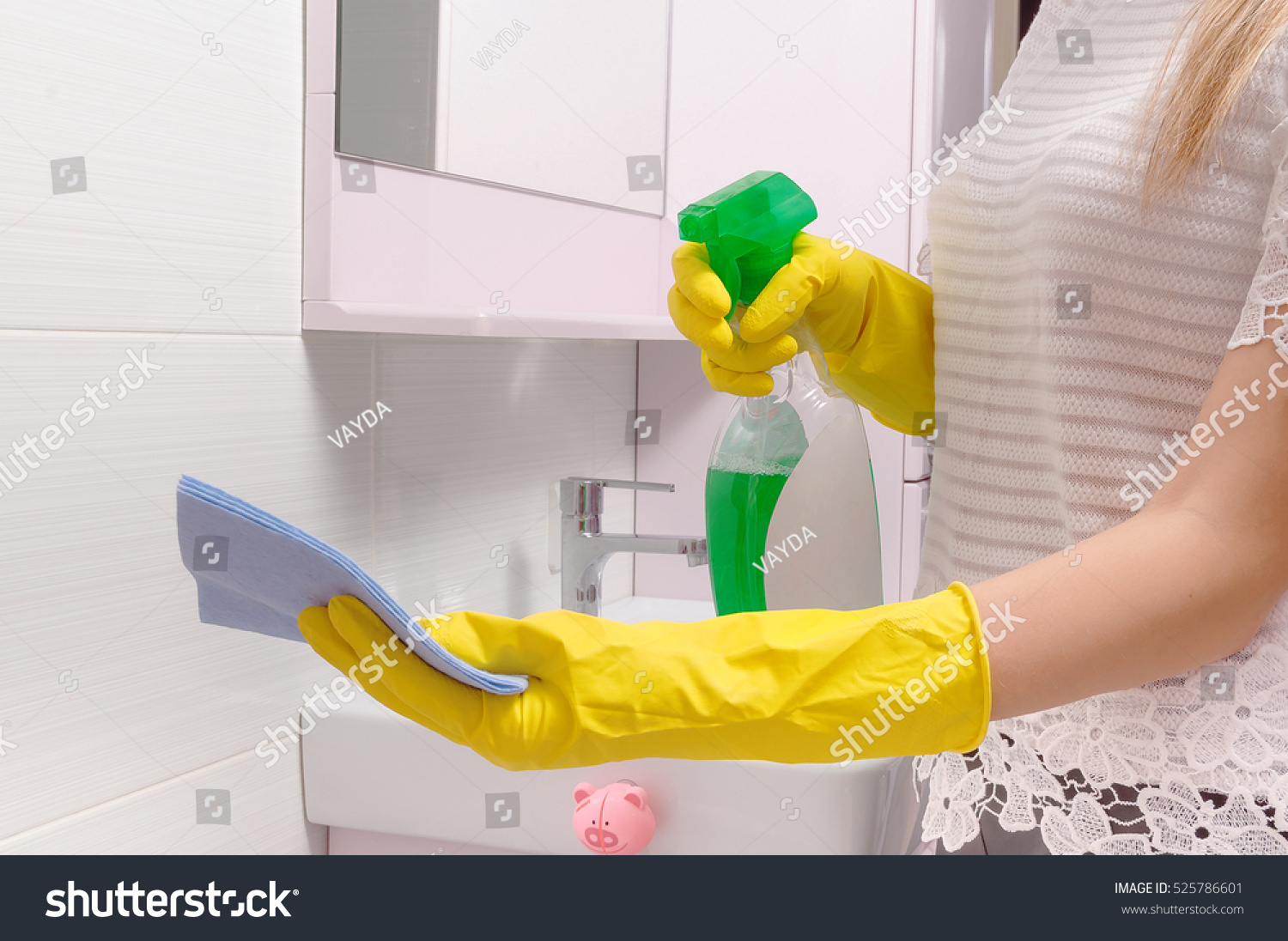 Cleanness in every move. Woman cleans mirror with help of green cloth and special mean of cleaning #525786601