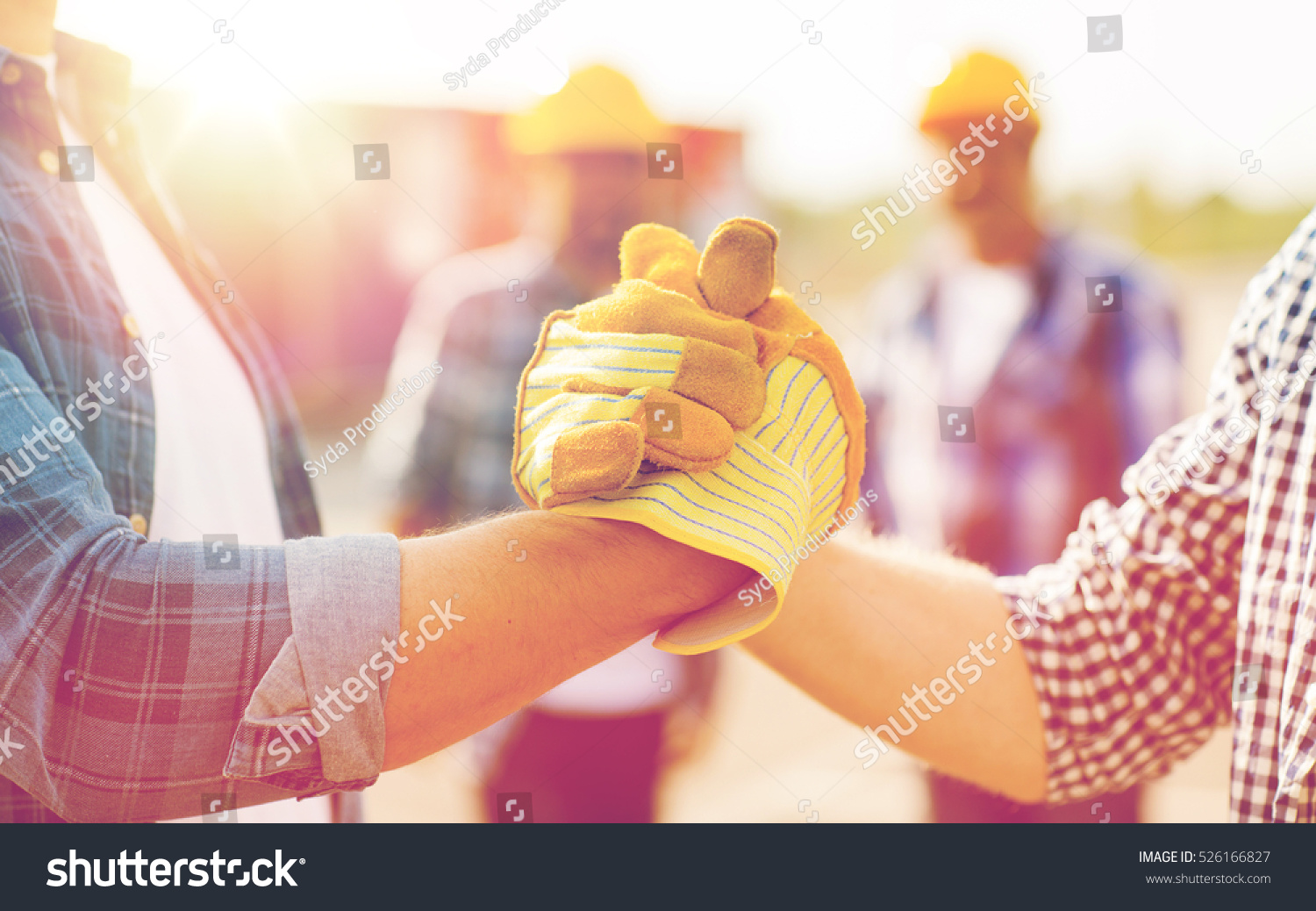 building, teamwork, partnership, gesture and people concept - close up of builders hands in gloves greeting each other with handshake on construction site #526166827