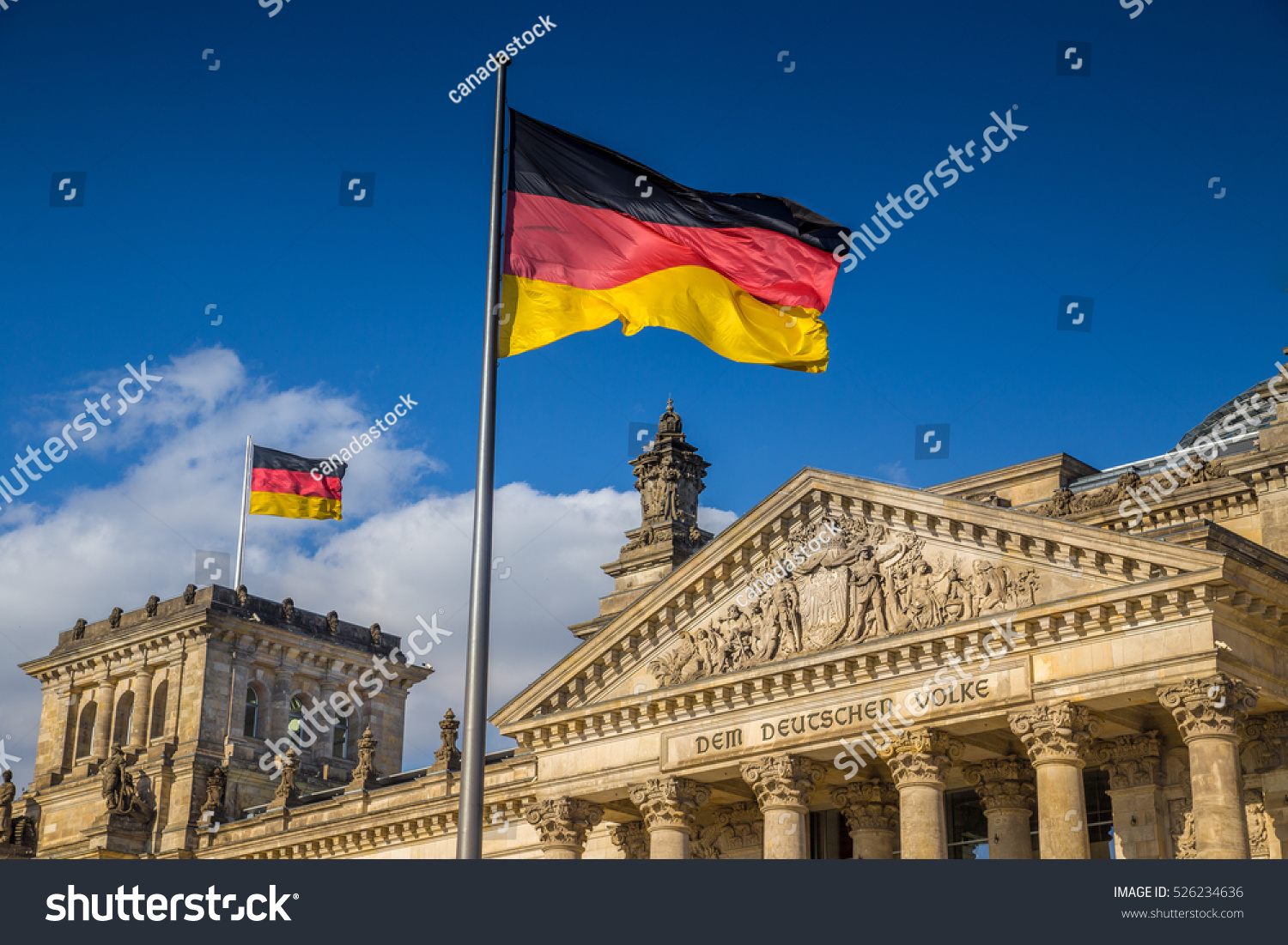 German flags waving in the wind at famous Reichstag building, seat of the German Parliament (Deutscher Bundestag), on a sunny day with blue sky and clouds, central Berlin Mitte district, Germany #526234636