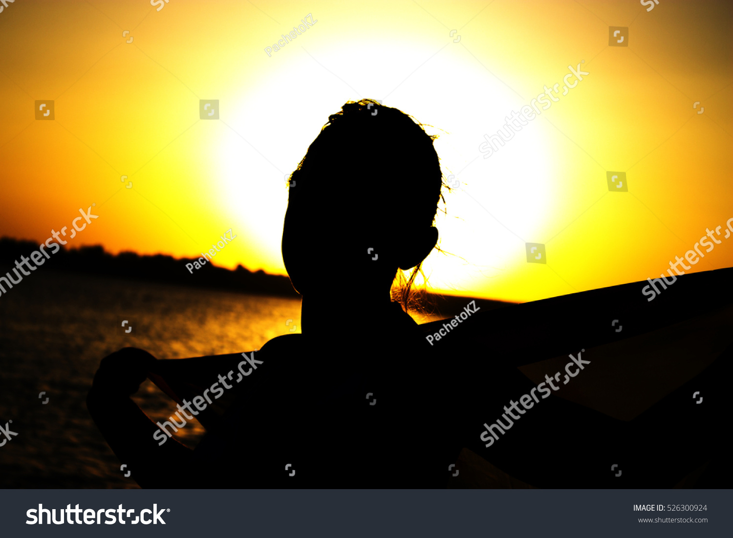 Evening on seashore. Silhouette of girl with handkerchief in his hands at sunset. #526300924