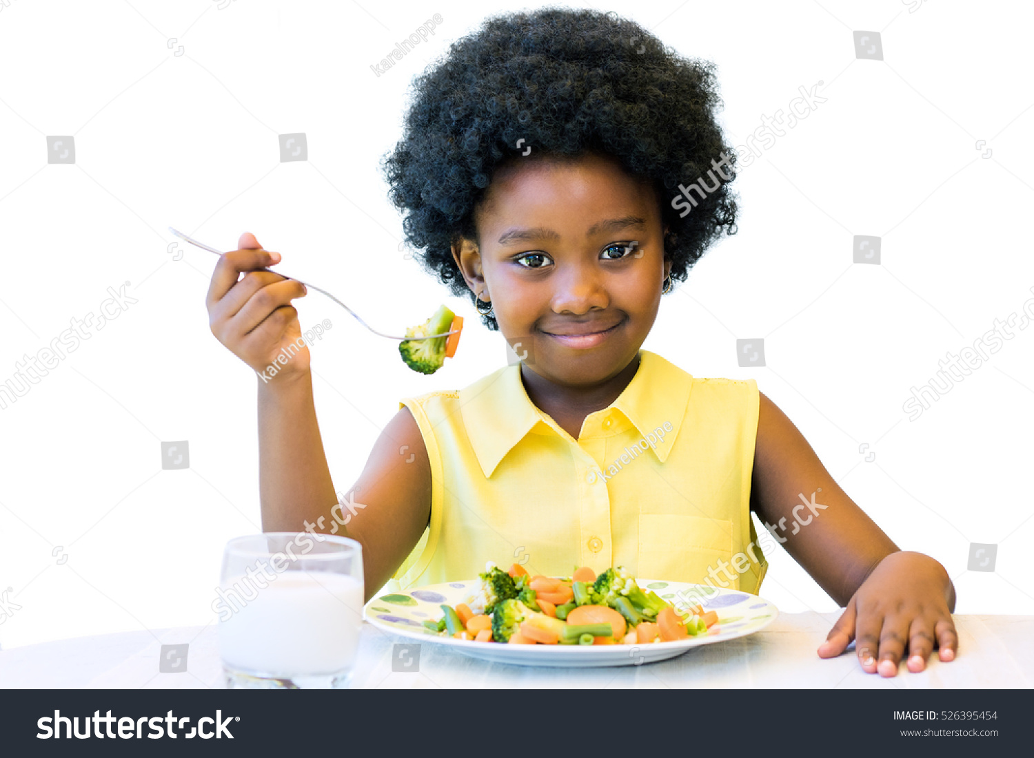 Close up portrait of cute african girl with afro hairstyle eating healthy vegetable dish. Isolated on white. #526395454