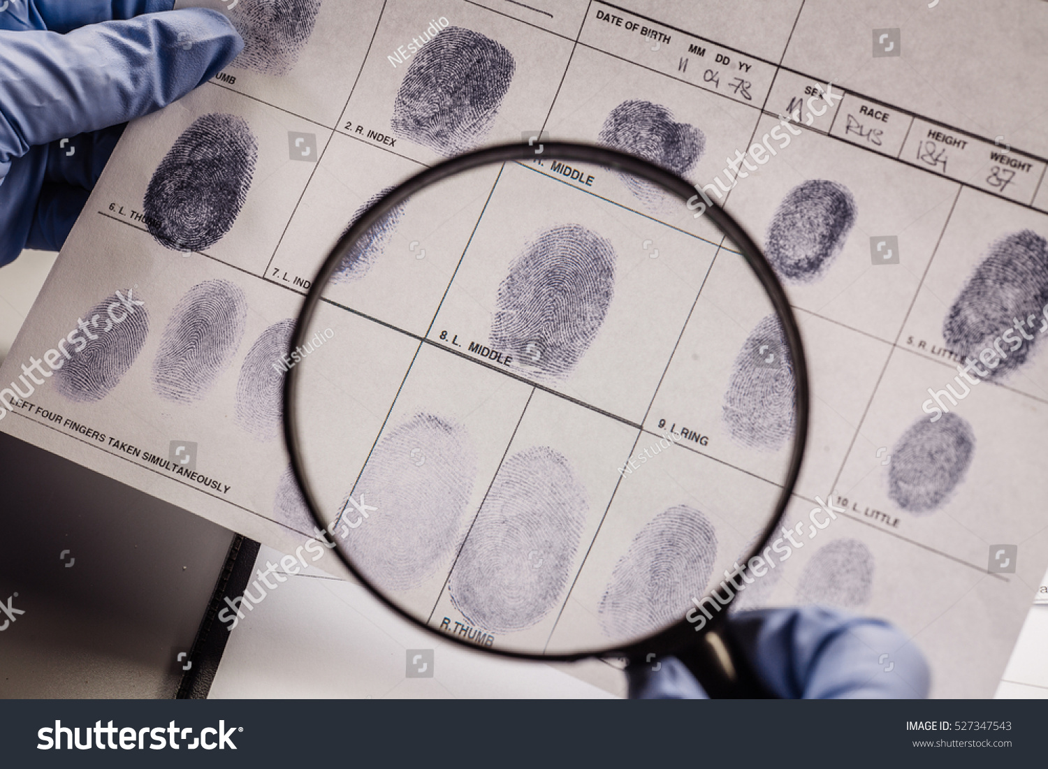 Criminology expert through a magnifying glass looking at a fingerprint #527347543