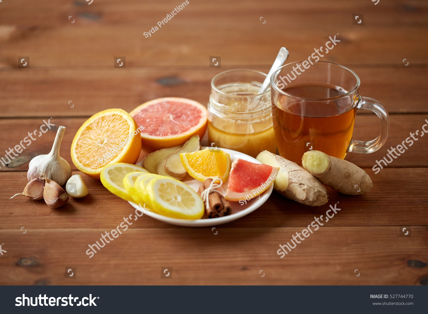 health, traditional medicine, folk remedy and ethnoscience concept - cup of ginger tea with honey, citrus and garlic on wooden background #527744770