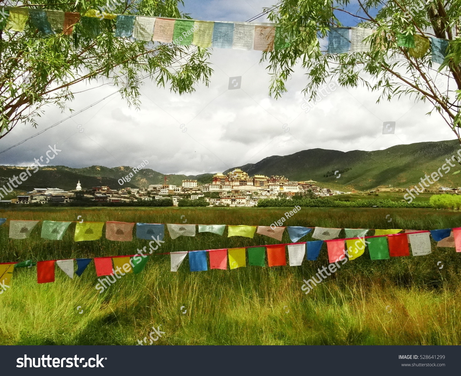 Colorful Buddhist Prayer flags across the lake near Songzanln Monastery in Shangri-La, Yunnan, China, near Tibet  (Tibetan Buddhism, Vajrayana) situated above the lake and among the green mountains. #528641299