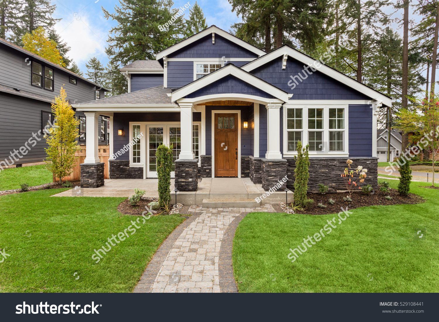Beautiful exterior of newly built luxury home. Yard with green grass and walkway lead to ornately designed covered porch and front entrance.  #529108441