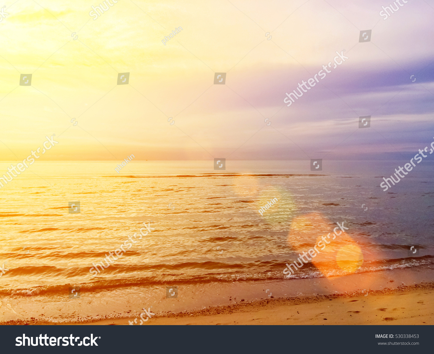 Blurred beach and calm sea waves on sunset background. Vintage landscape blur warm soft relax. Natural colors sun light in summer. Abstract bokeh flare virtual sunrise in tropic horizon beautiful. #530338453