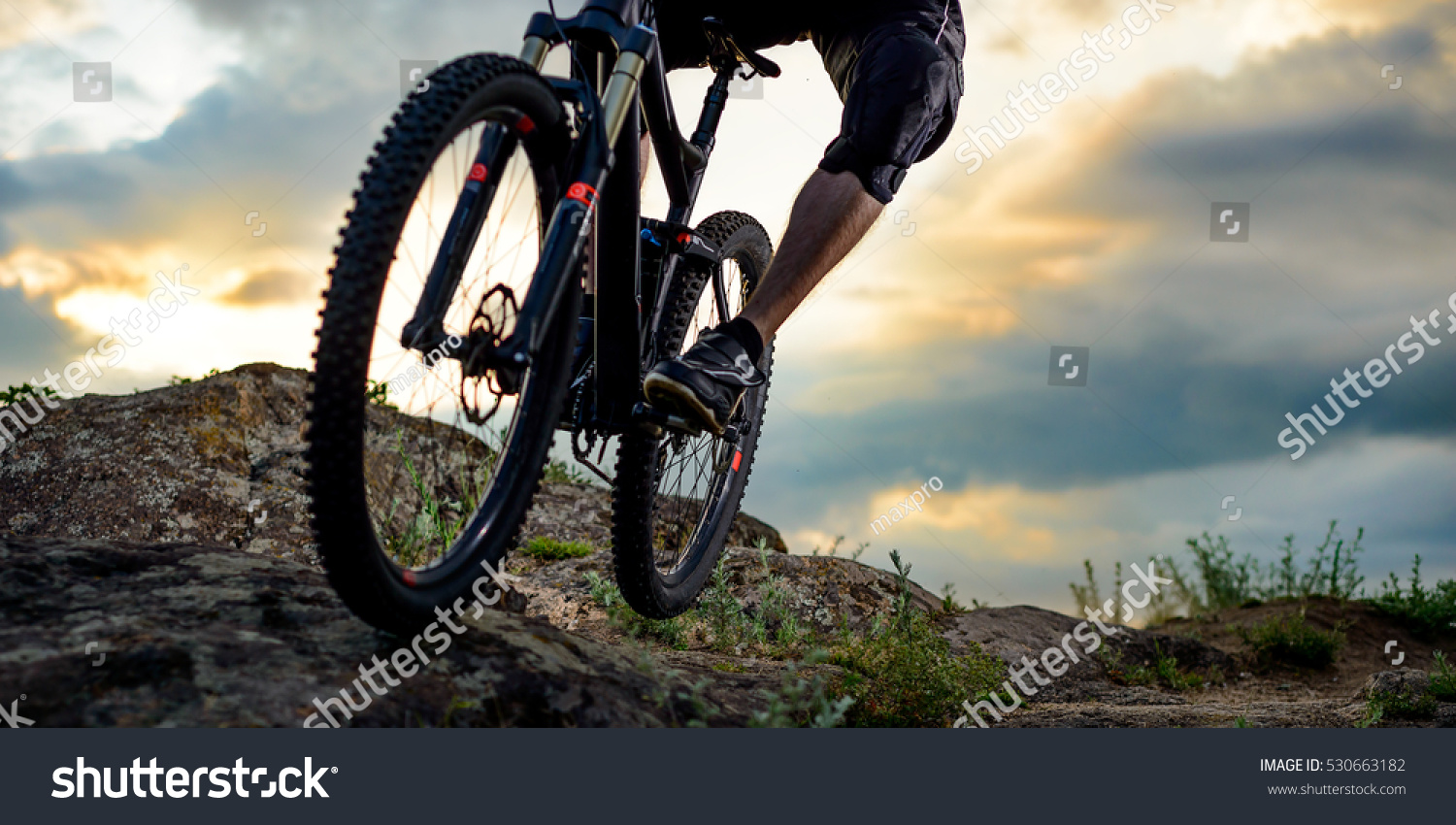Cyclist Riding the Bike Down Rocky Hill at Sunset. Close up Extreme Sport Concept. Space for Text. #530663182