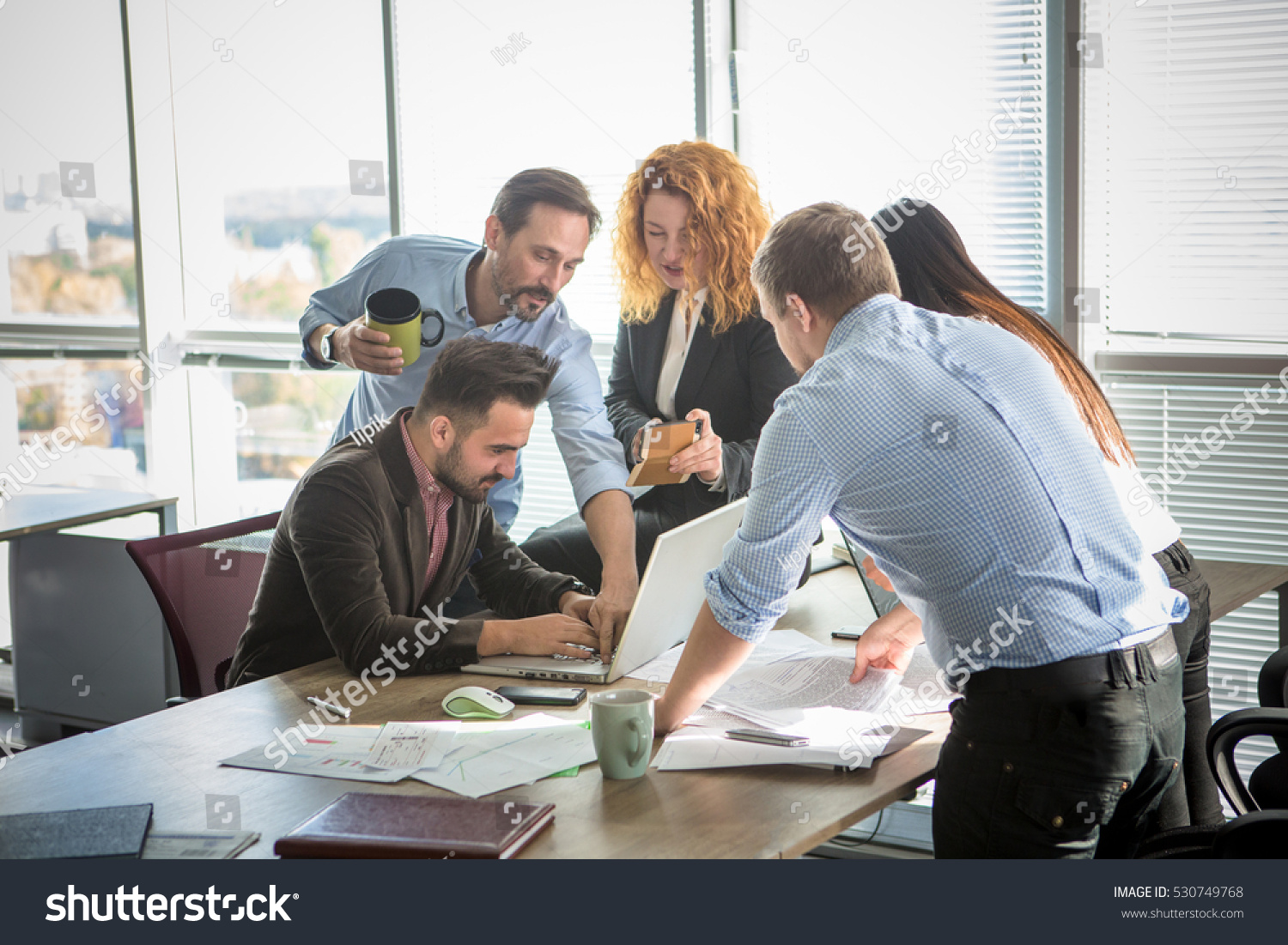 Business people showing team work while working in board room in office interior. People helping one of their colleague to finish new business plan. Business concept. Team work. #530749768