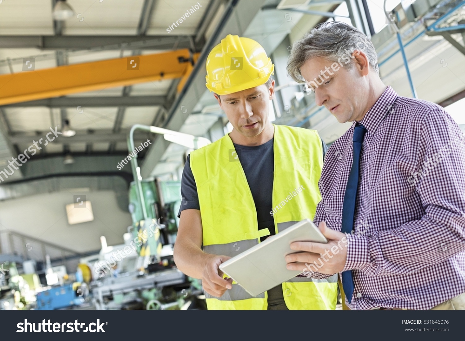 Supervisor and manual worker using digital tablet in metal industry #531846076