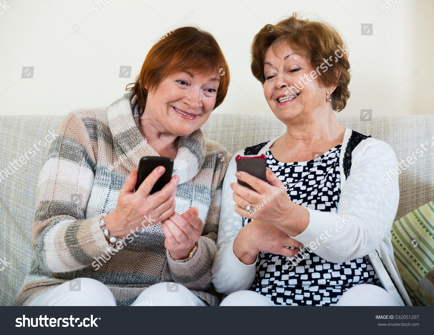 Happy smiling  mature women browsing internet on smarthphones indoor #532051207