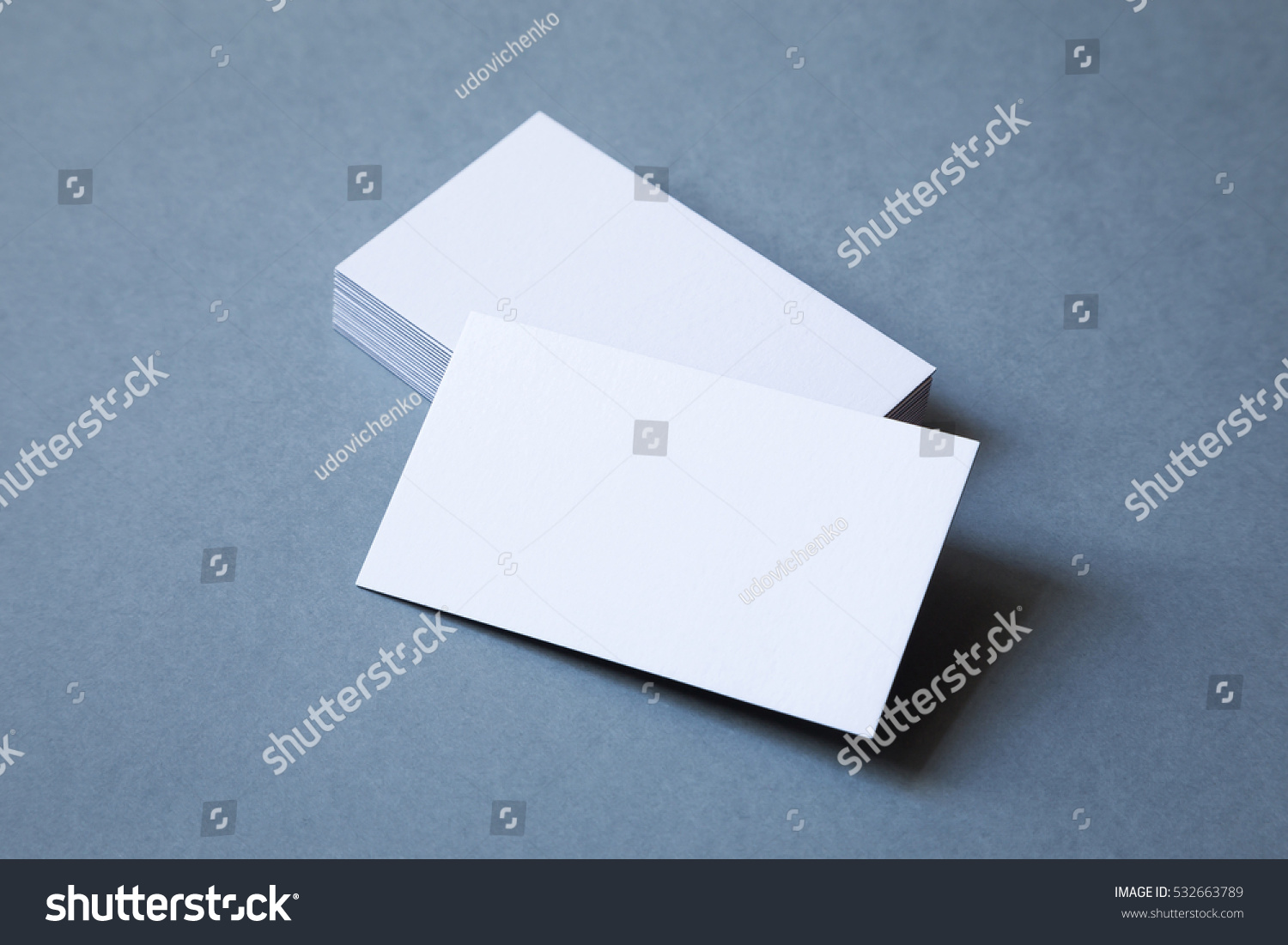 Stack of thick blank business cards on a grey background, top view. The top card is shifted to front. #532663789