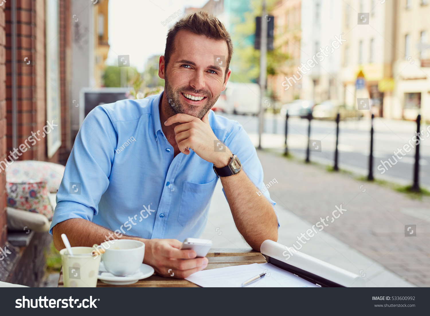 Happy man having coffee break at outdoors cafe during nice summer day #533600992