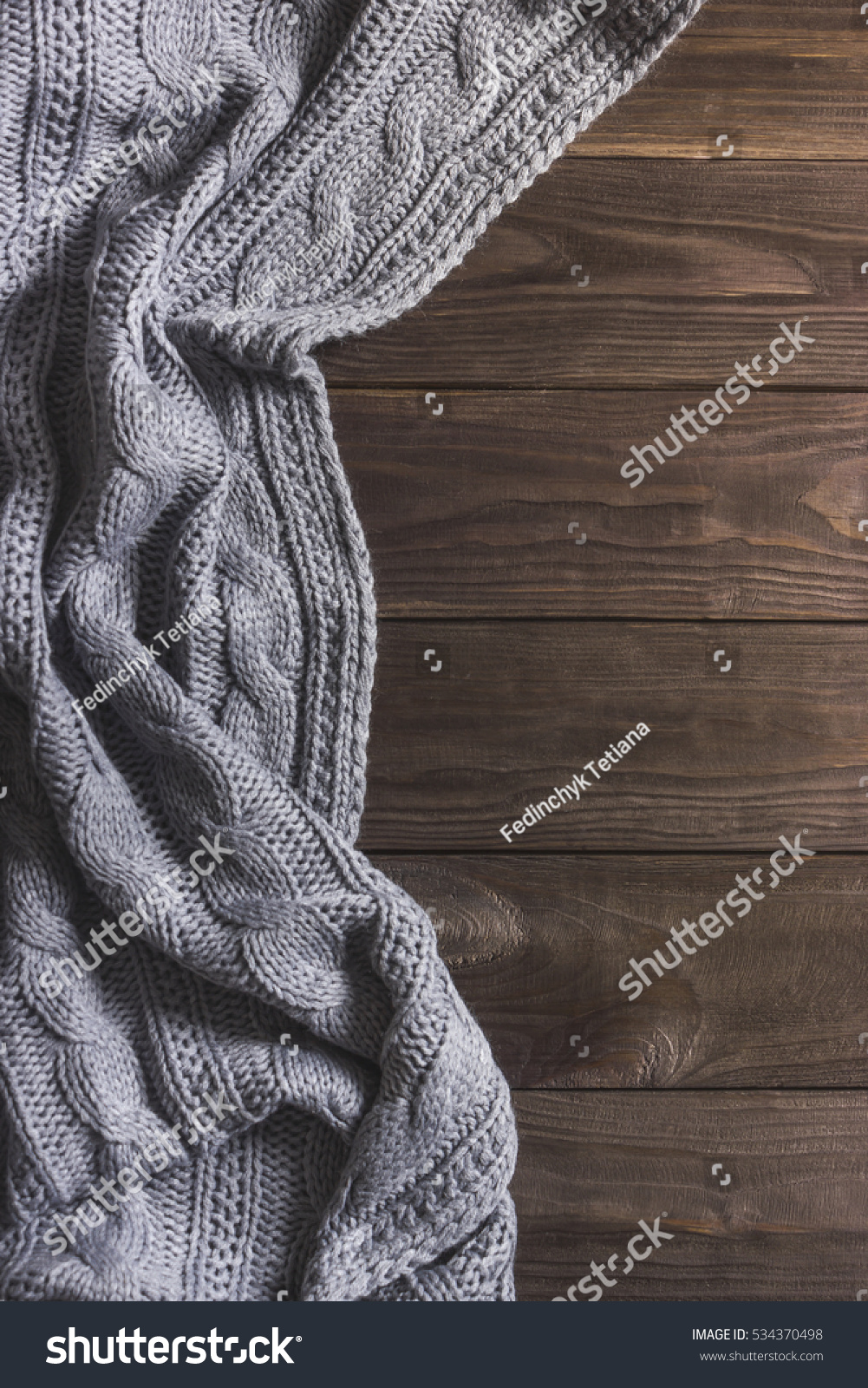 Warm Knitted crumpled gray blanket on a wooden background. Top view, space for text #534370498
