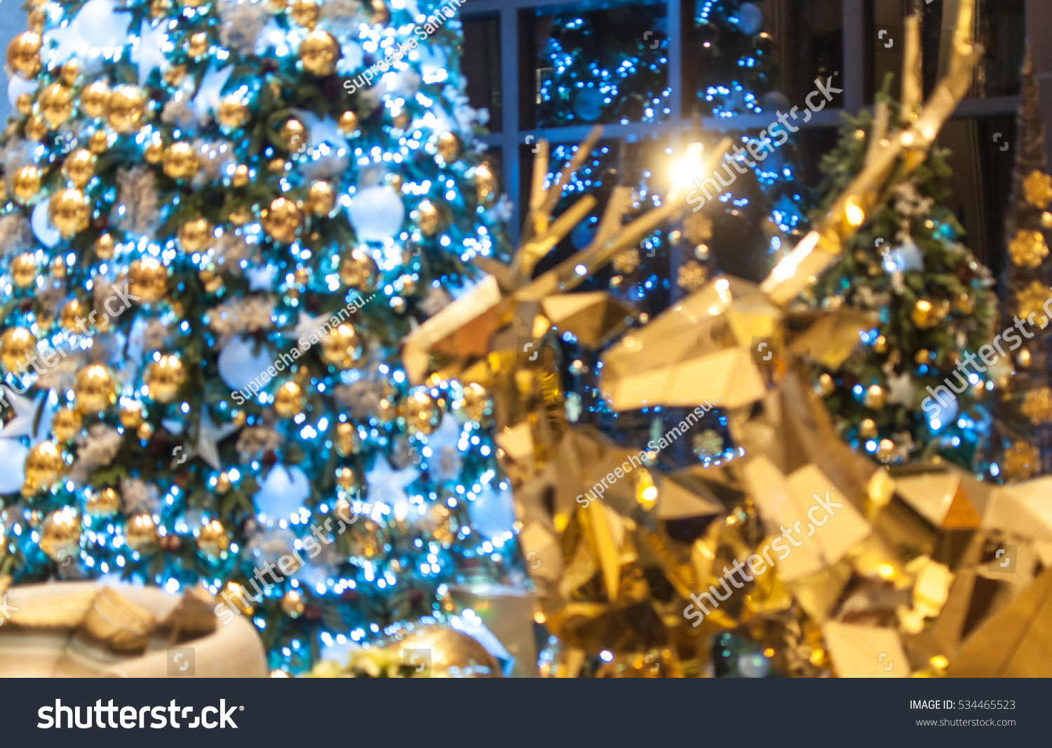 Bokeh background of Christmas tree and golden reindeer. Blurred background. Christmas theme. #534465523