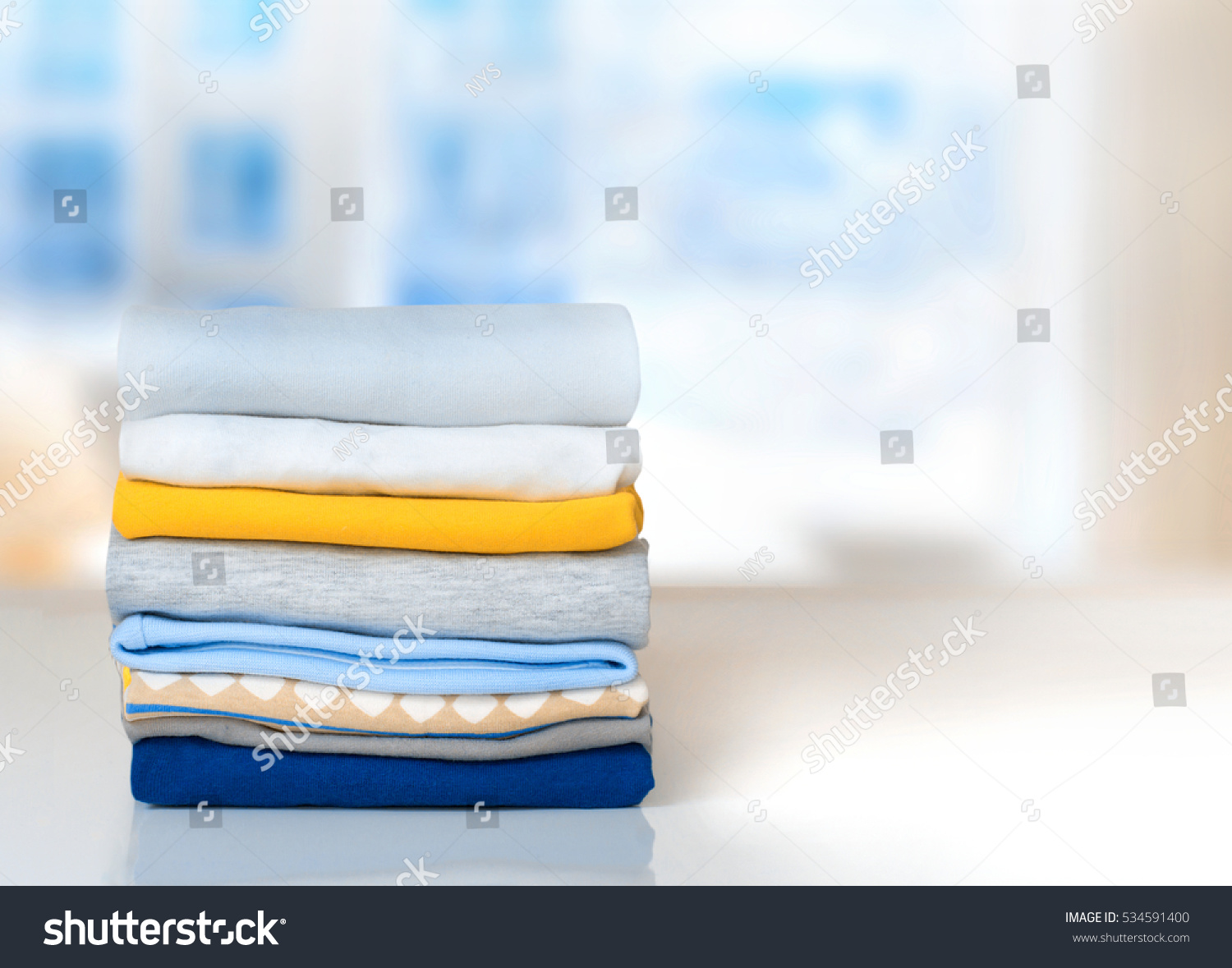 Cotton stack of colorful folded clothes on white table indoors empty space background.Household concept.Clean laundry pile. #534591400
