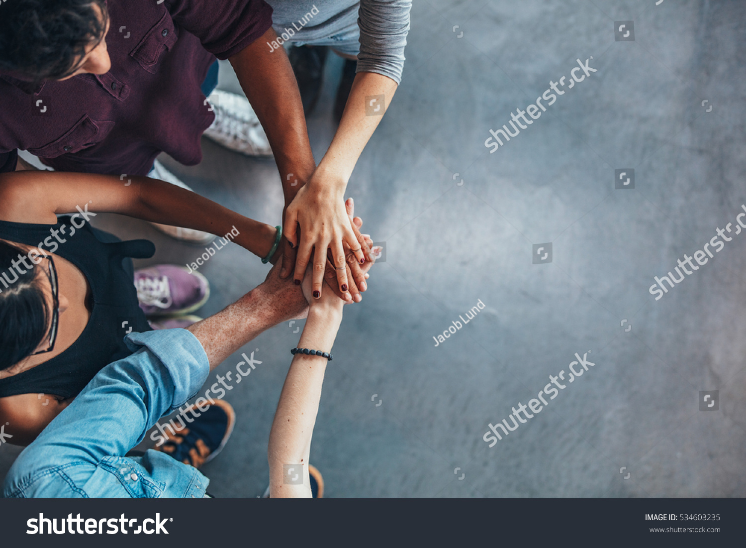 Top view image of group of young people putting their hands together. Friends with stack of hands showing unity. #534603235